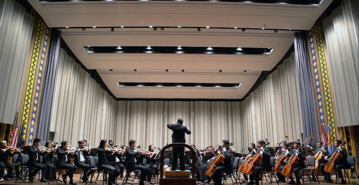 musicians on a stage with a conductor on the podium