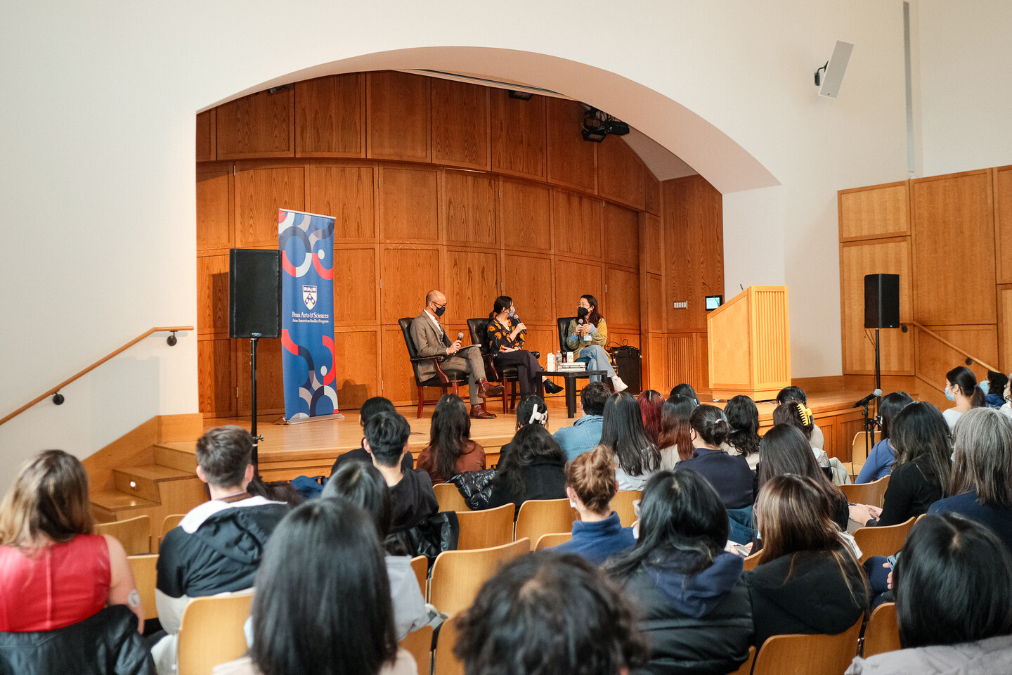 The Widener auditorium, showing a crowd listening to three people on a stage.