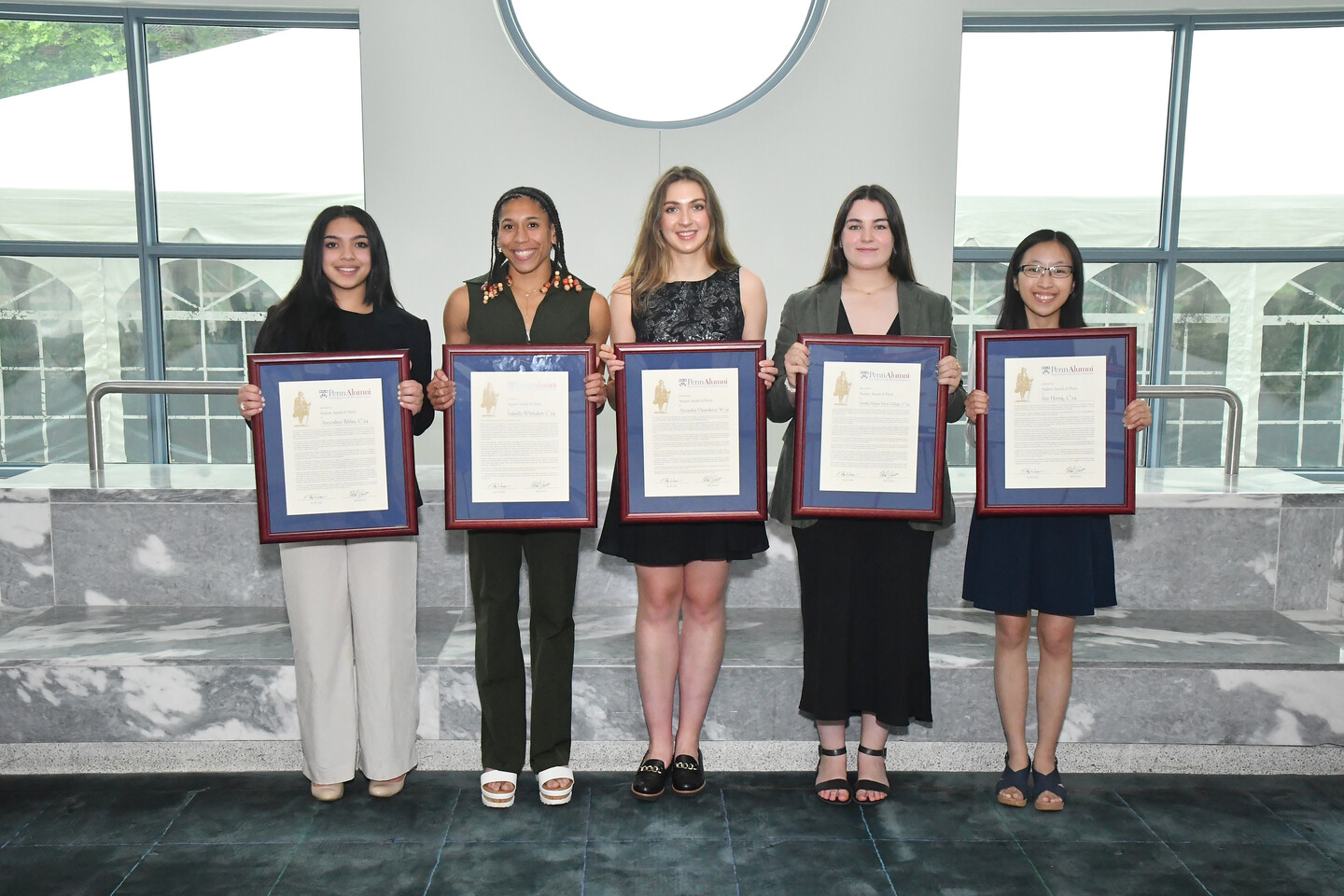 Five people stand with framed awards