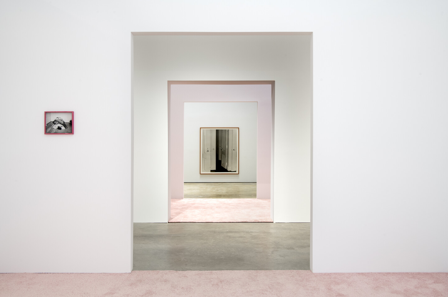 Series of carpeted rooms with photographs displayed on the walls.