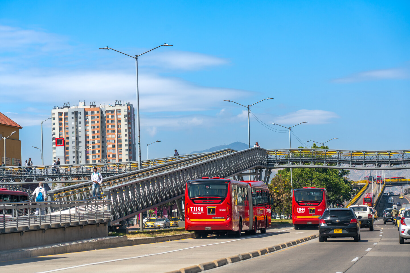 Transmilenio station with iron bridges with articulated buses on a sunny day, Bogotá. Colombia