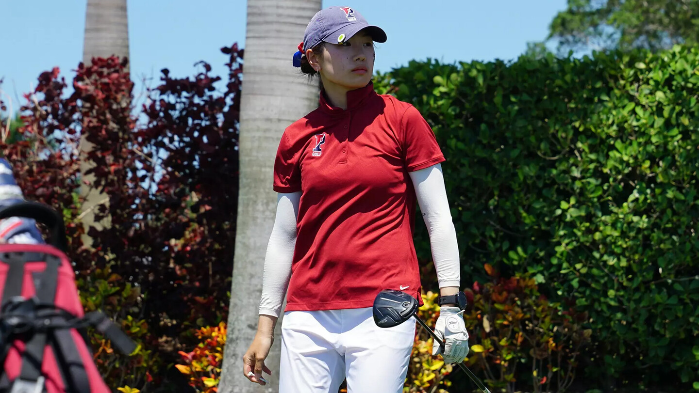 Julie Shin watches her ball during a match while holding her club.