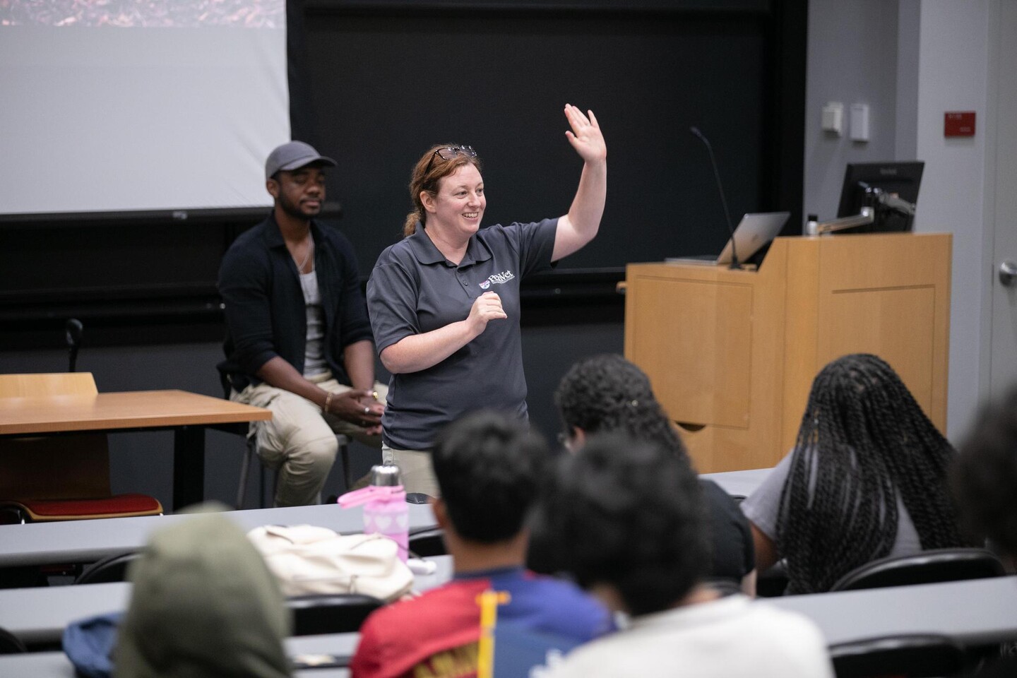 Instructor raising hand in front of students.