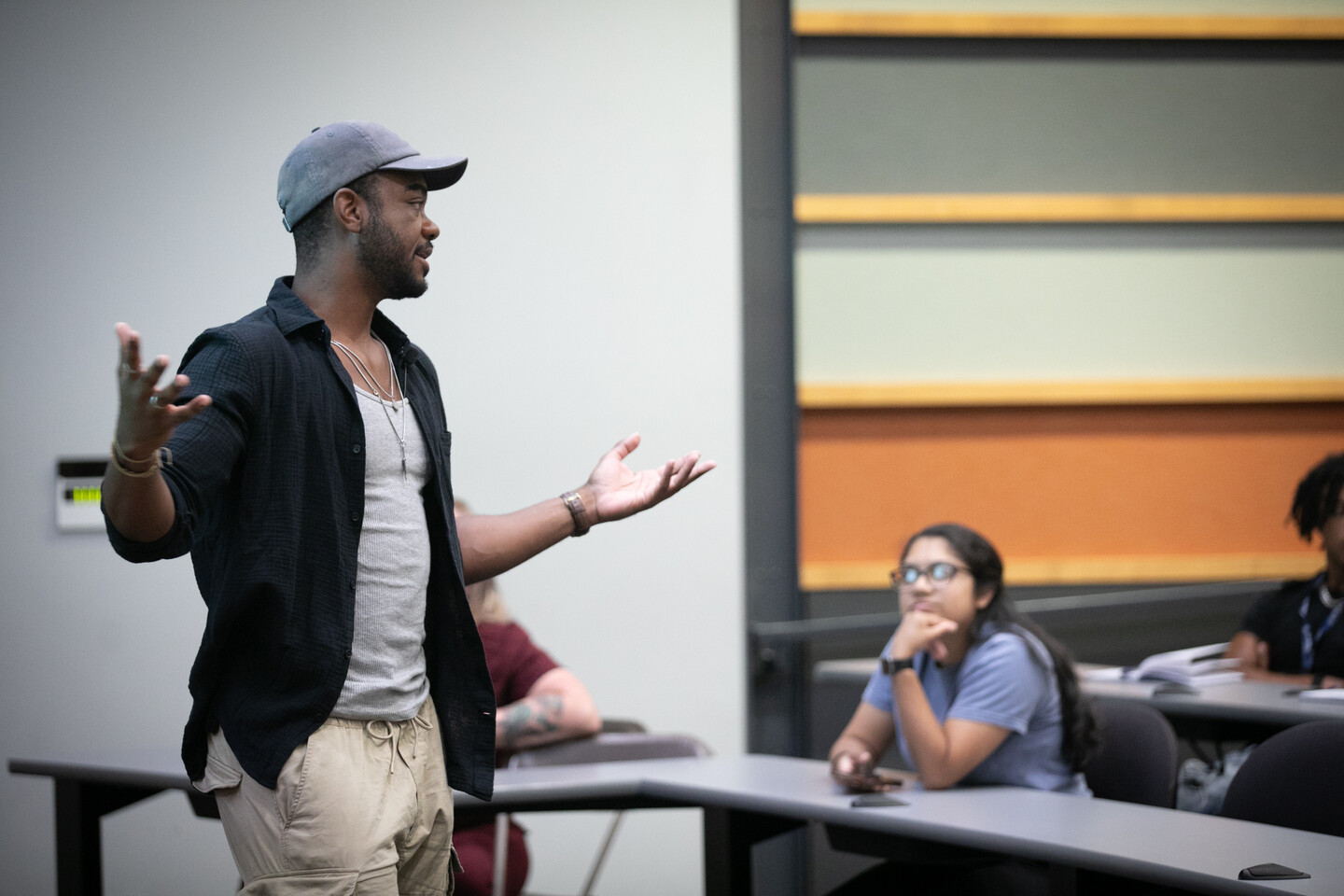 Speaker gestures in front of a classroom of students.