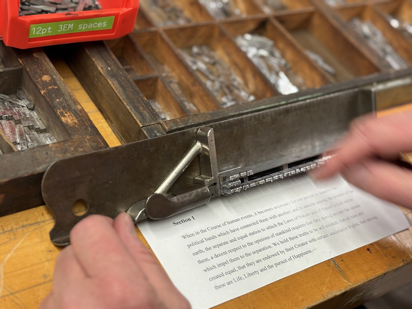 A hand preparing letterpress off a small paper with text.