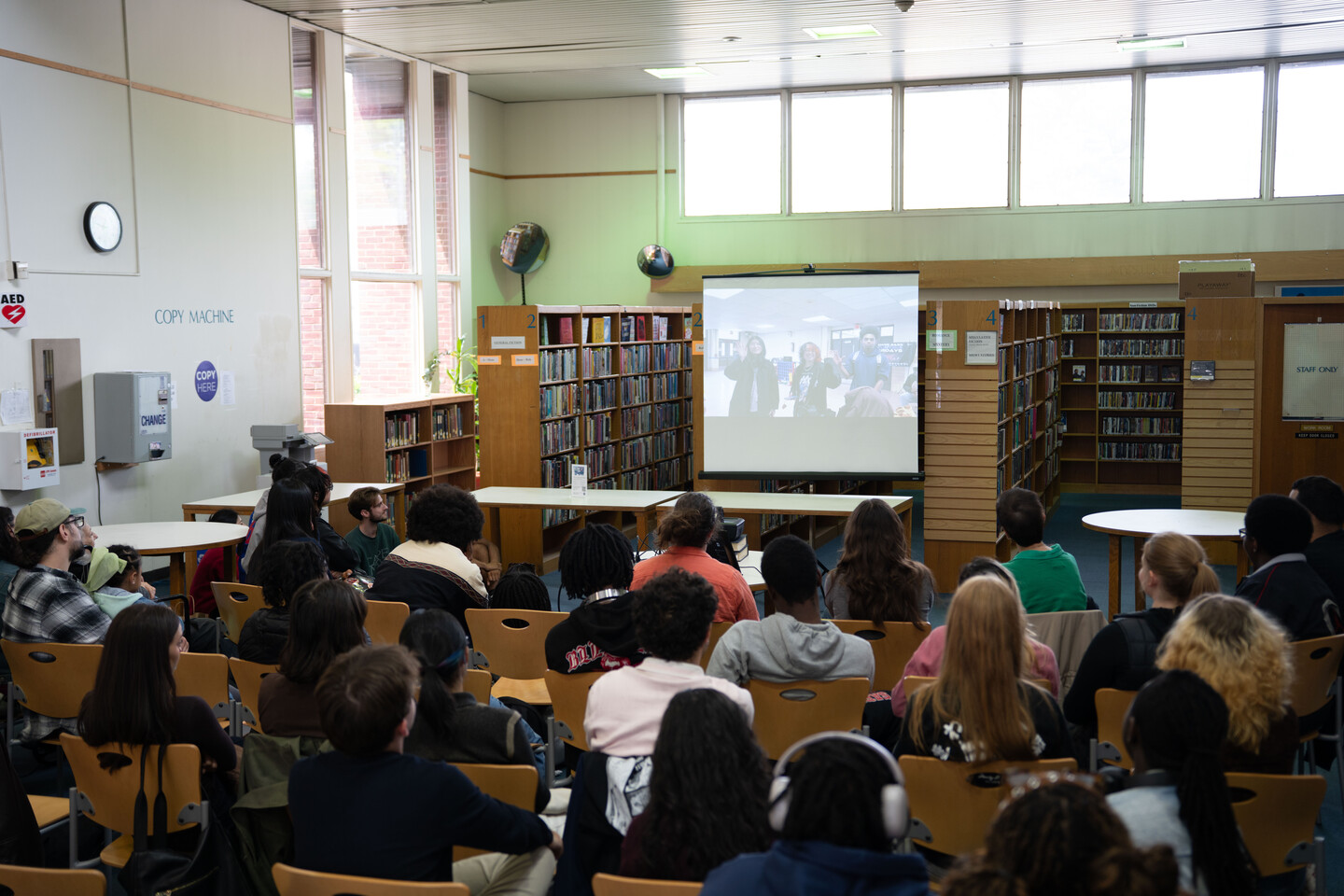 students in a school library watching a video.