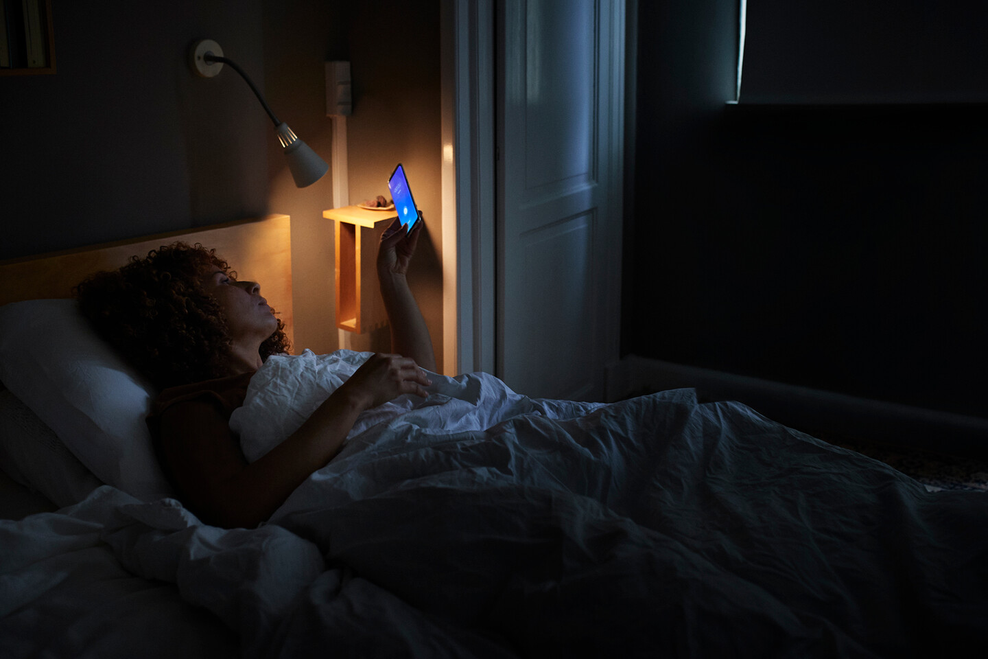 A person looking at a smartphone in bed