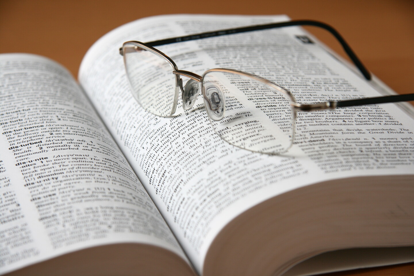 An open dictionary with a pair of glasses on an open page.
