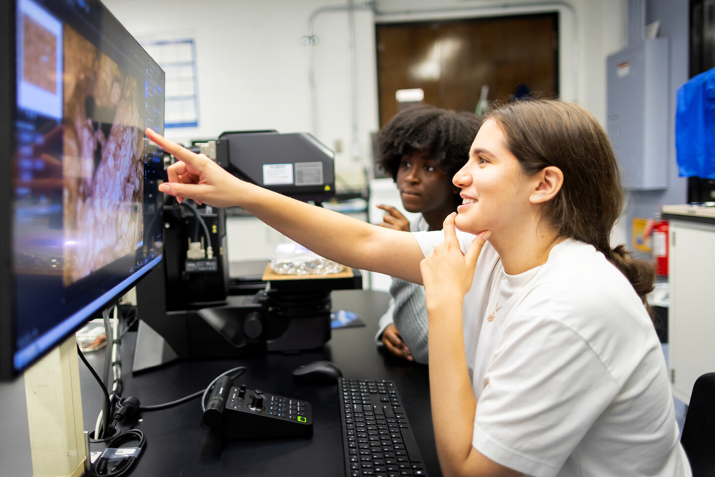 Nafisa Bangura and Angelica Dadda doing hands-on experimental work with CoolSeal-treated asphalt bricks in the Composto Lab.