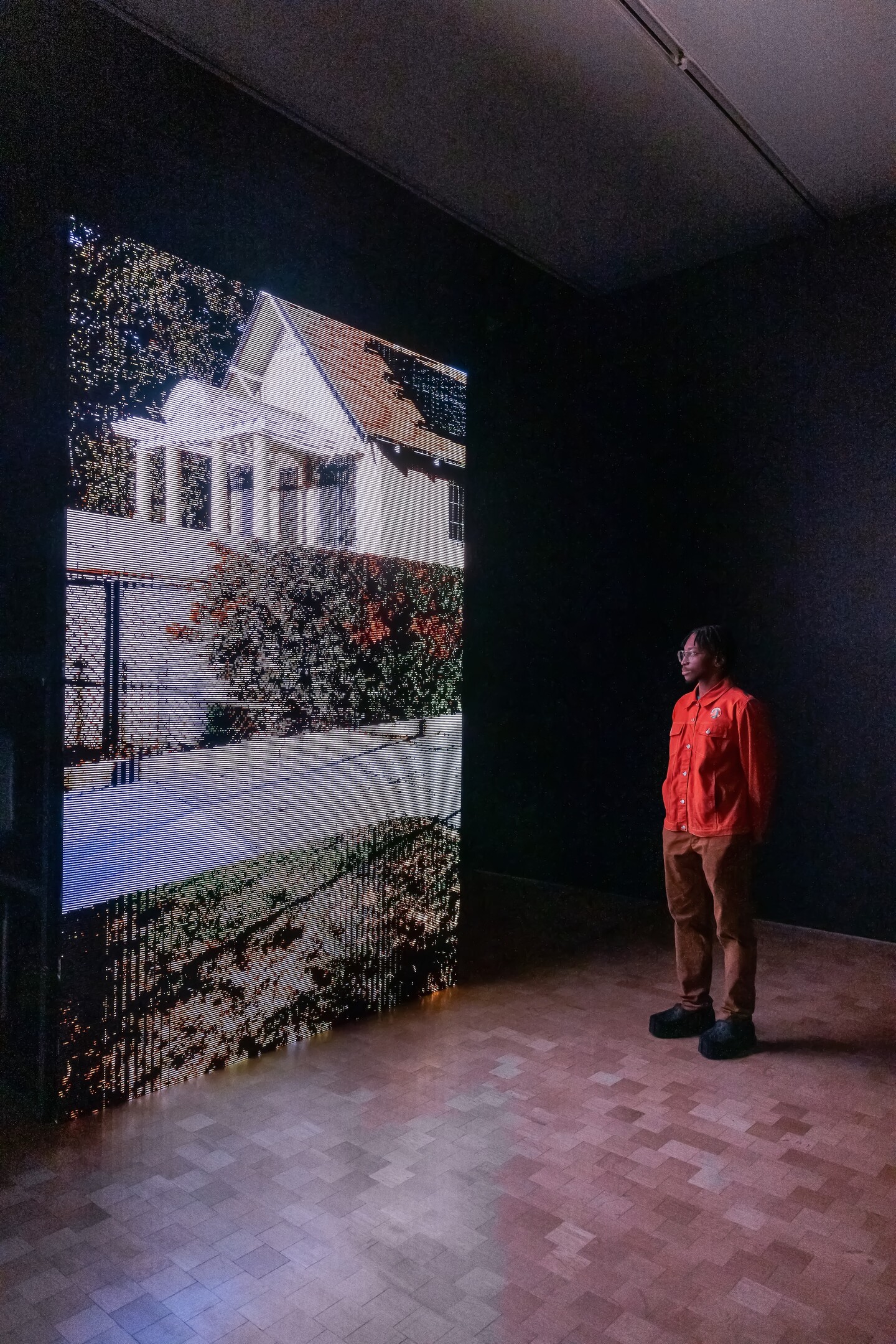 Person watches "On Exactitude in Science (Watts)" showing on screen at the Barnes.