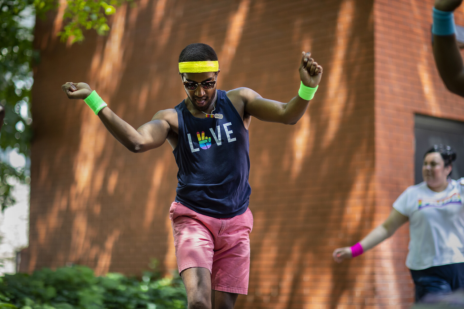 A person wearing a sweatband and wristbands dances outside in a Penn courtyard.