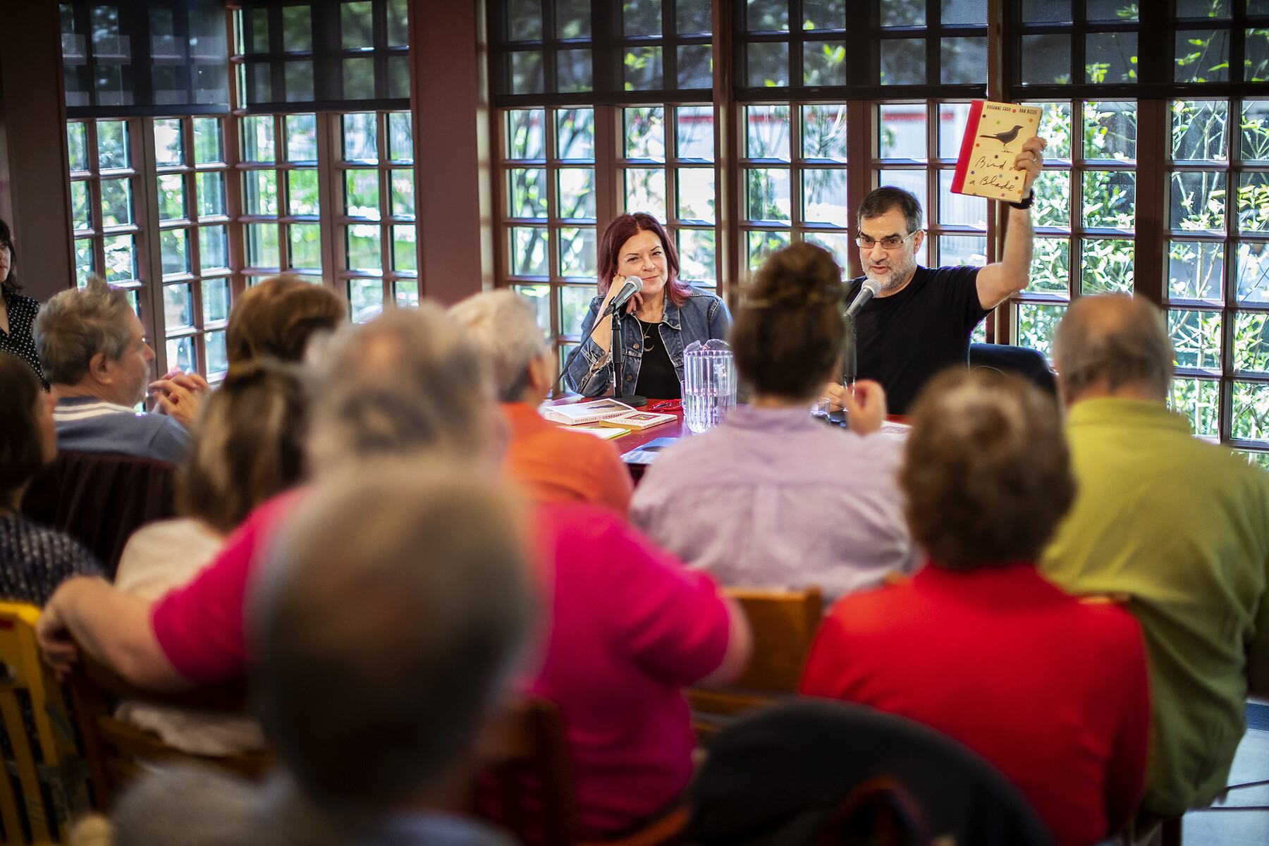 Roseanne Cash and Al Filreis seated at a table in front of a seated crowd at the Kelly Writers House.