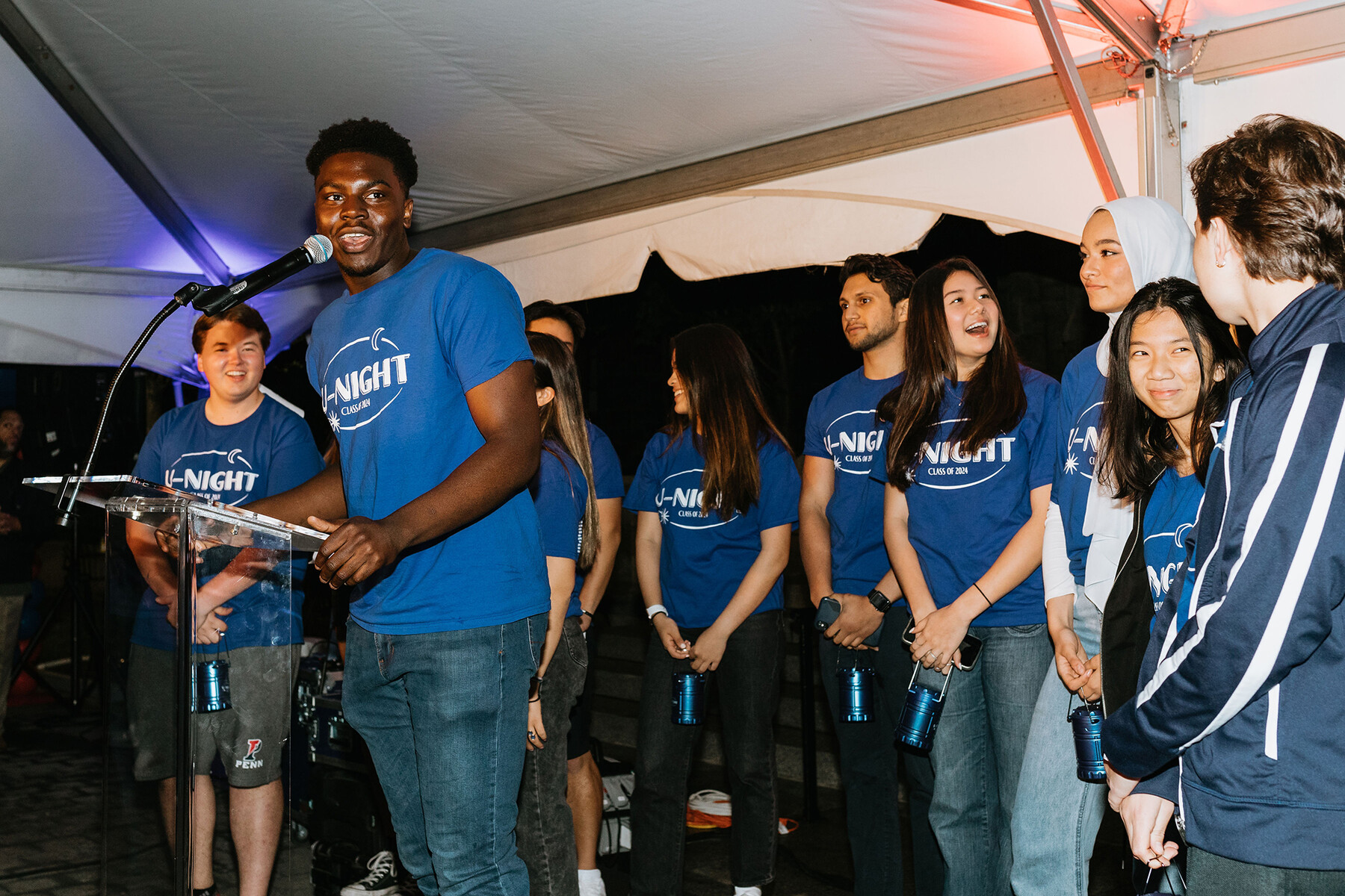 Members of Penn’s Class Board of 2024 standing near the Board president, who speaks into a microphone.