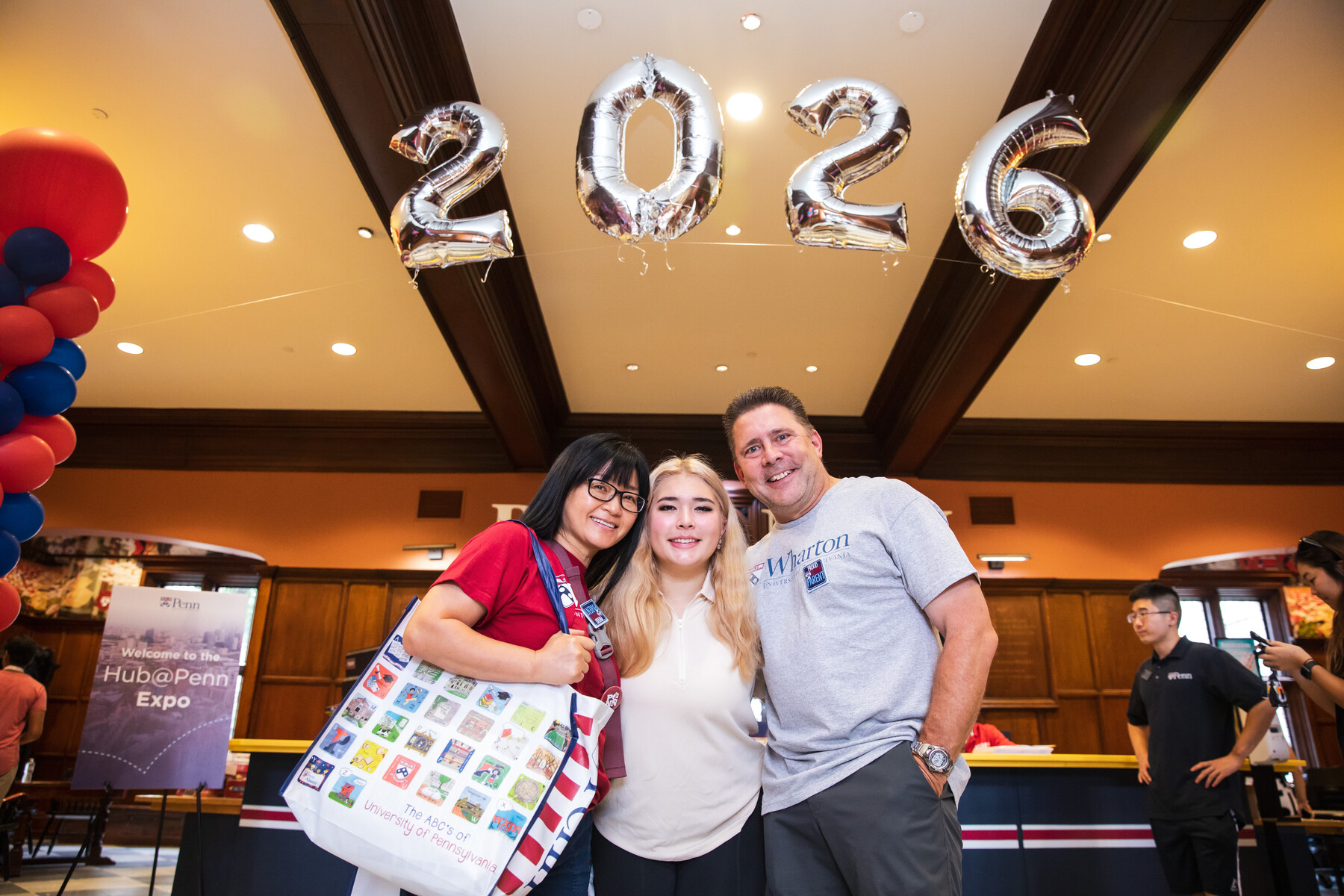 A student and their parents stand under a 2026 balloon display in Houston Hall.