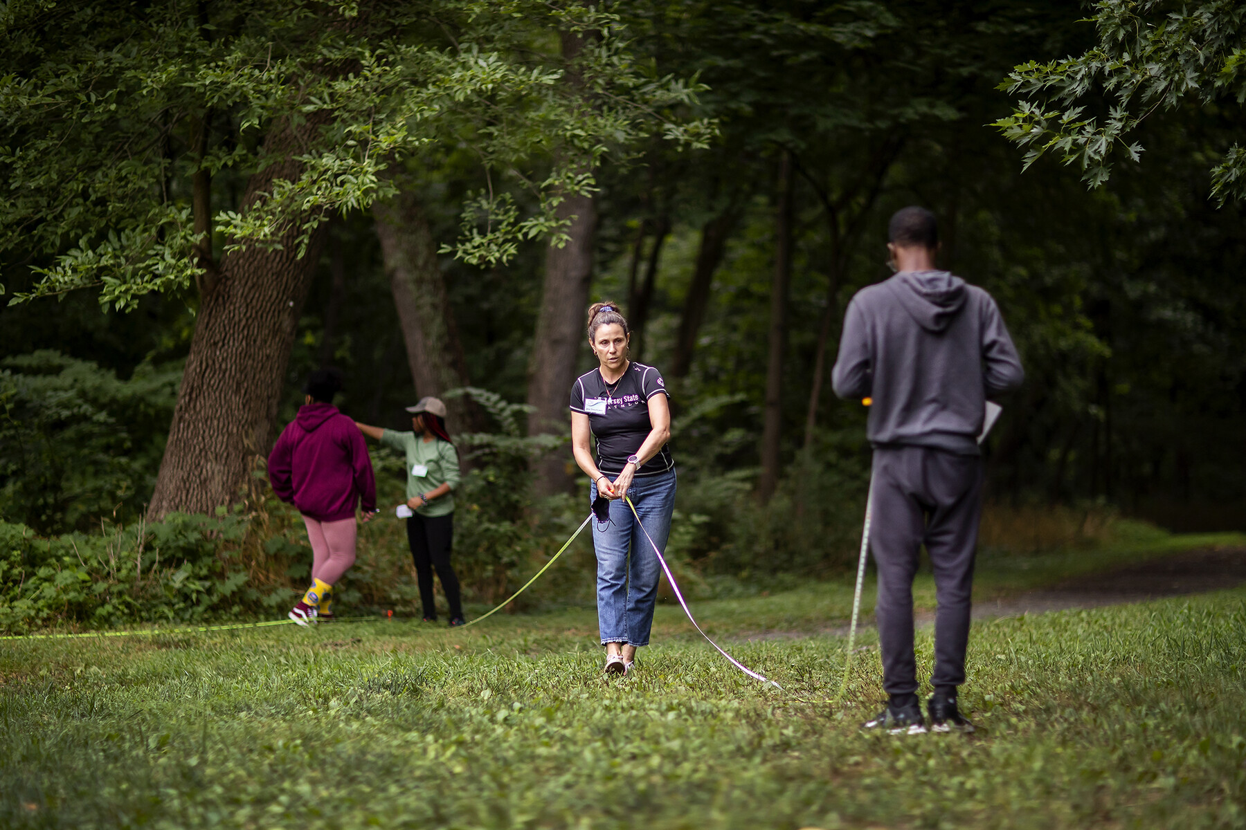 Four people outside at Cobbs Creek taking a measurement of the land.
