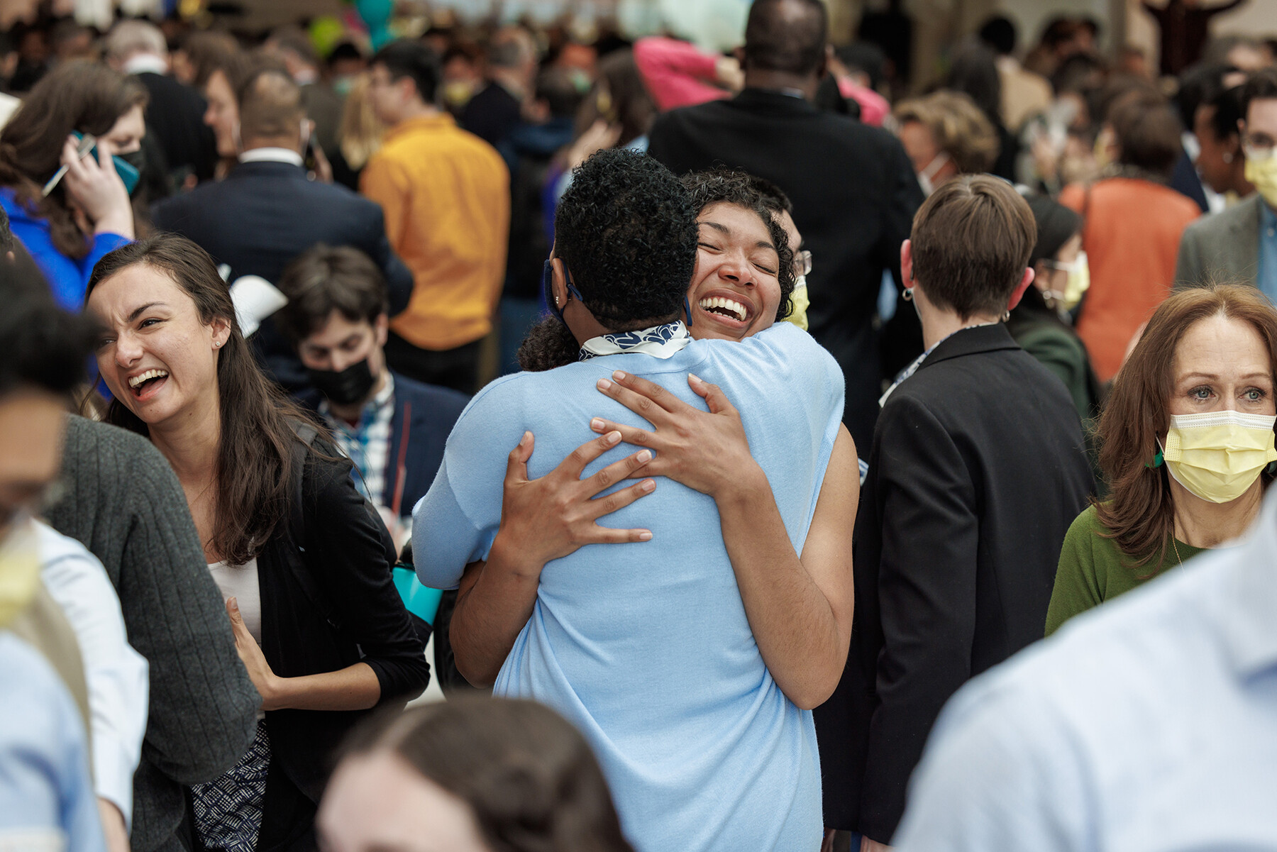 Two people hugging in a crowd in Penn Med's atrium.