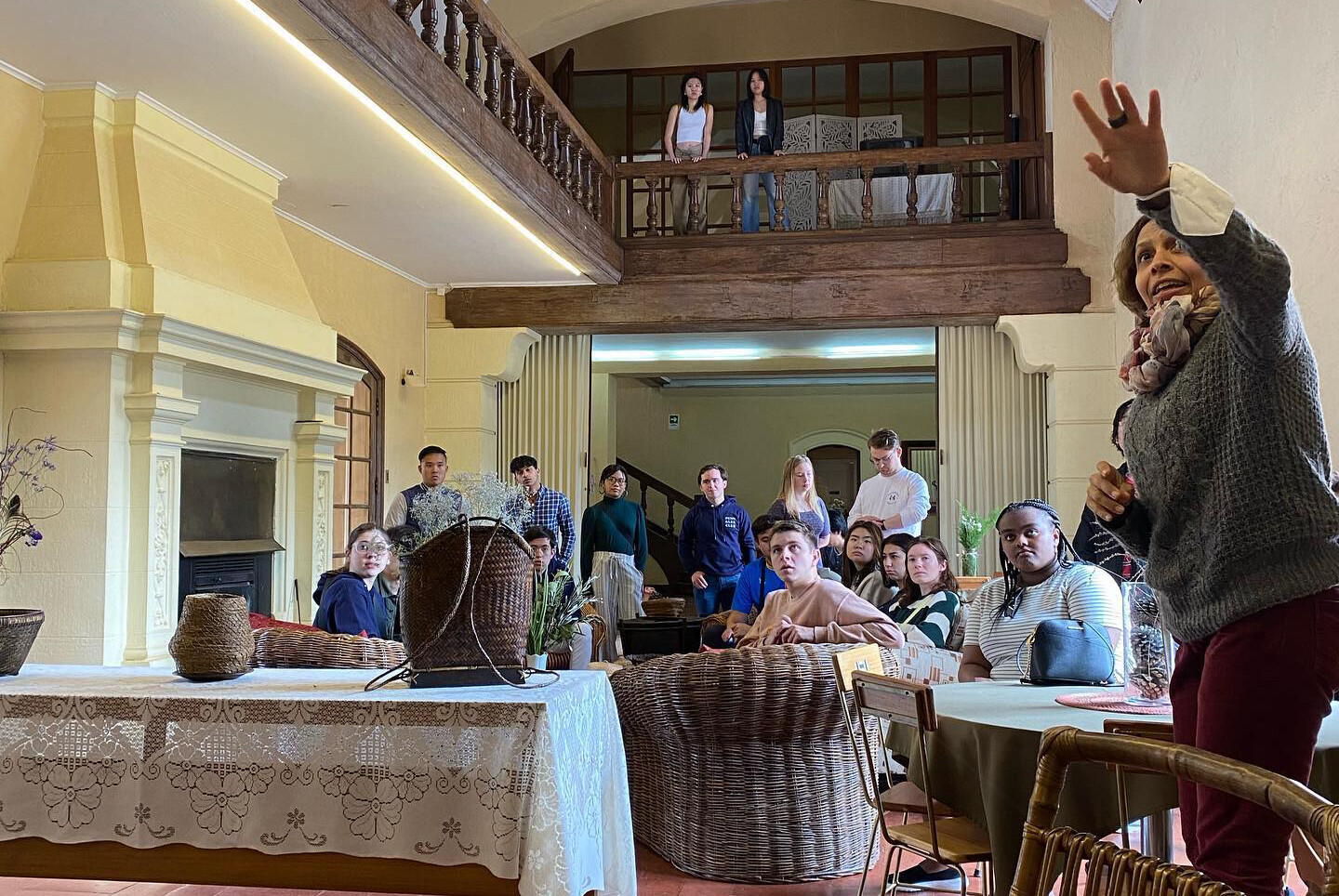 Members of Penn’s Glee Club in a historical building in Chile looking at something at a far wall being pointed out to them.