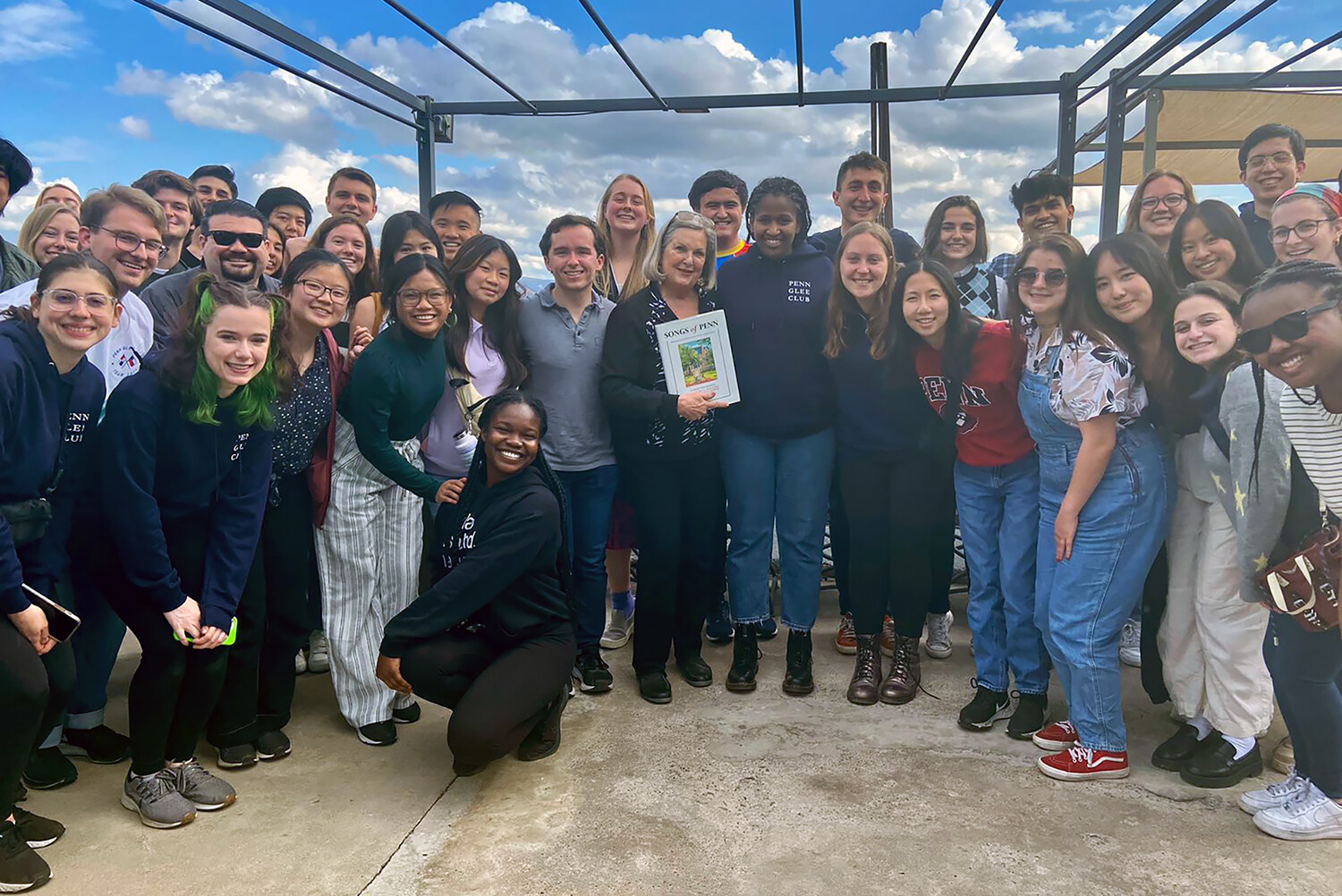 Members of Penn Glee Club posing as a group with a restaurant owner in Chile.