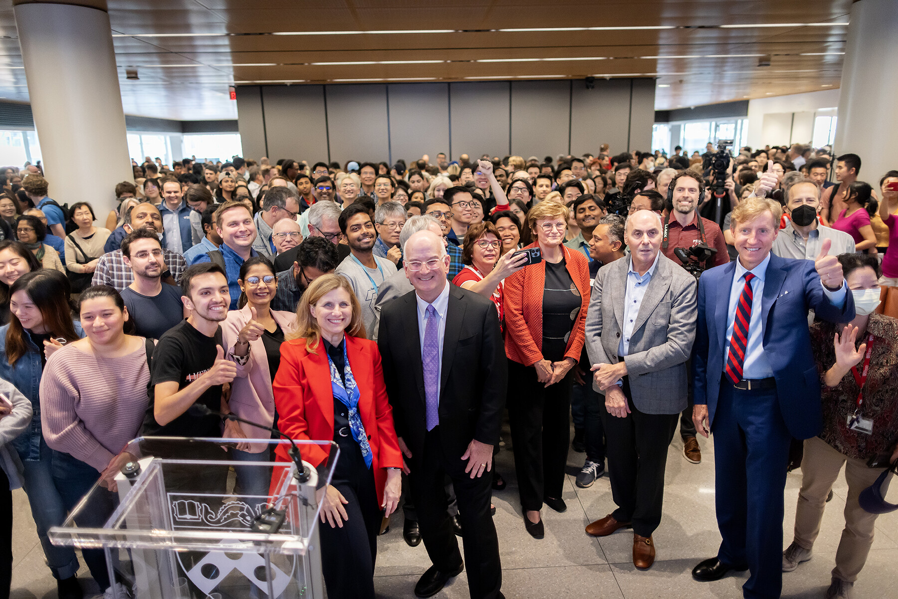 Katalin Kariko and Drew Weissman and a crowd of people at Penn Medicine, including J. Larry Jameson and Penn President Liz Magill.