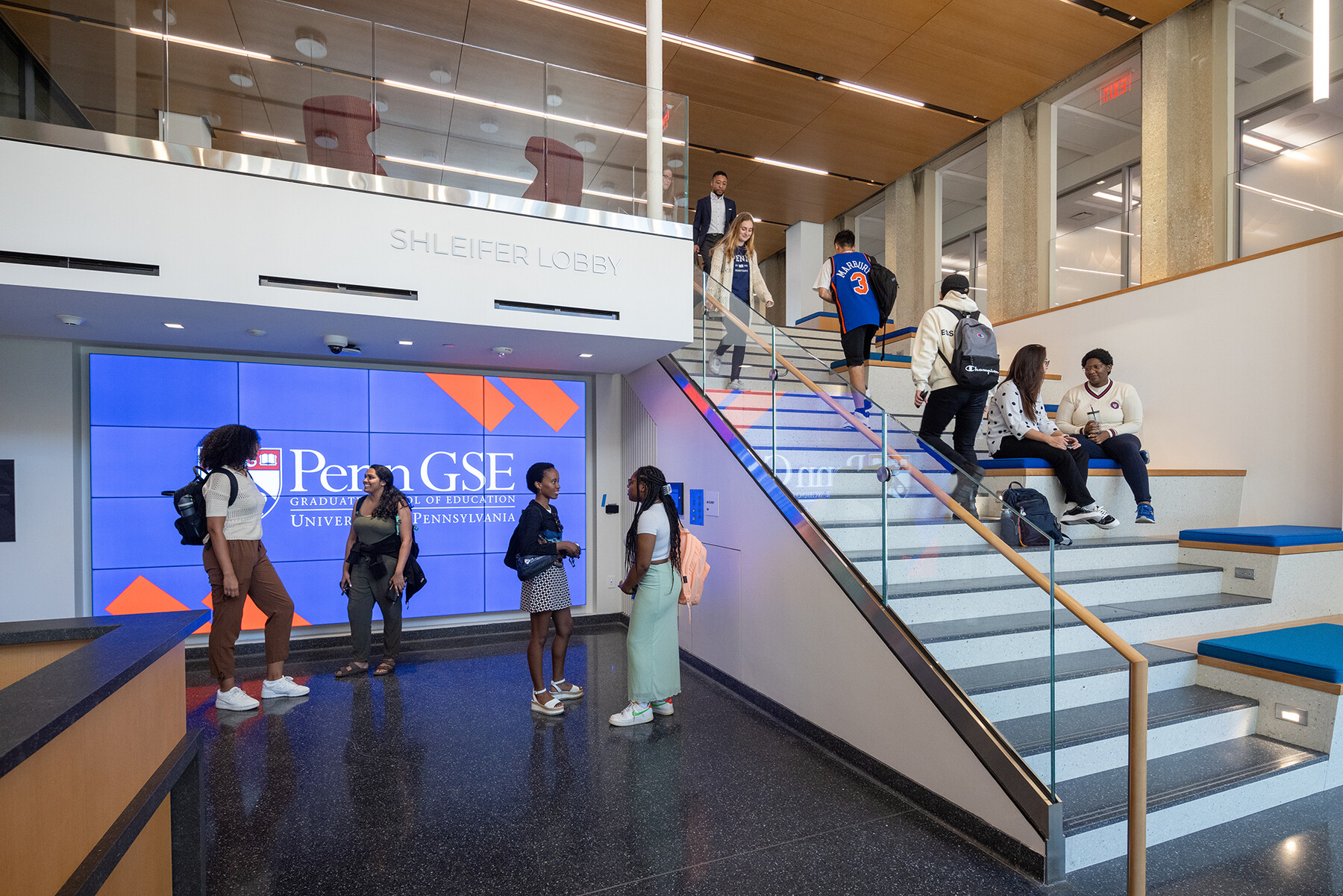 People standing in the lobby of Penn GSE and on the stairs.