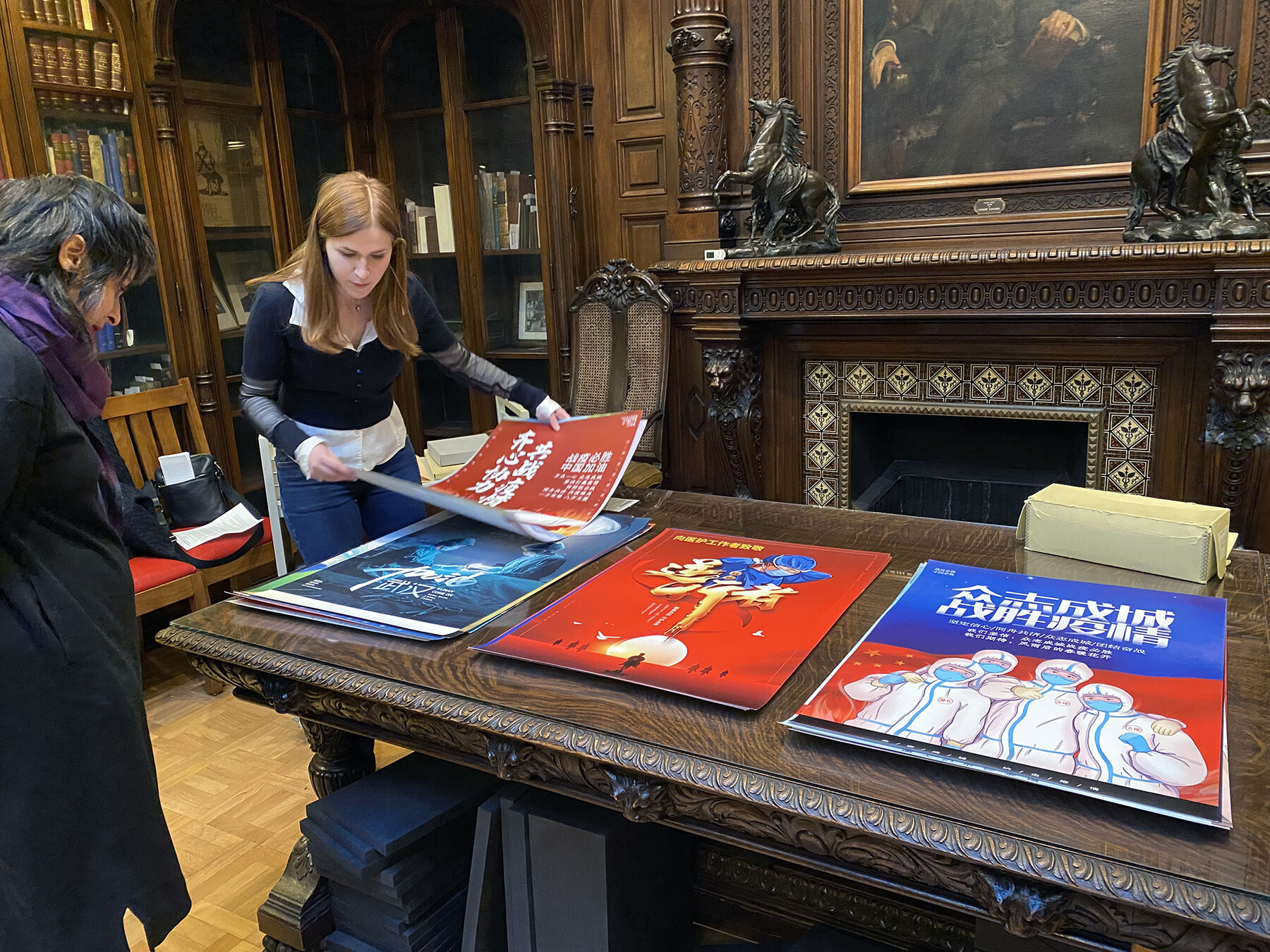 Two people looking at large COVID posters on a table in the Kislak Libary.