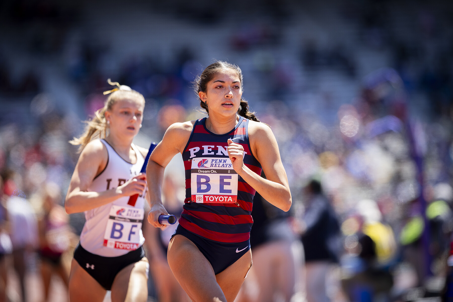 penn student runs in the 2024 penn relays with a baton