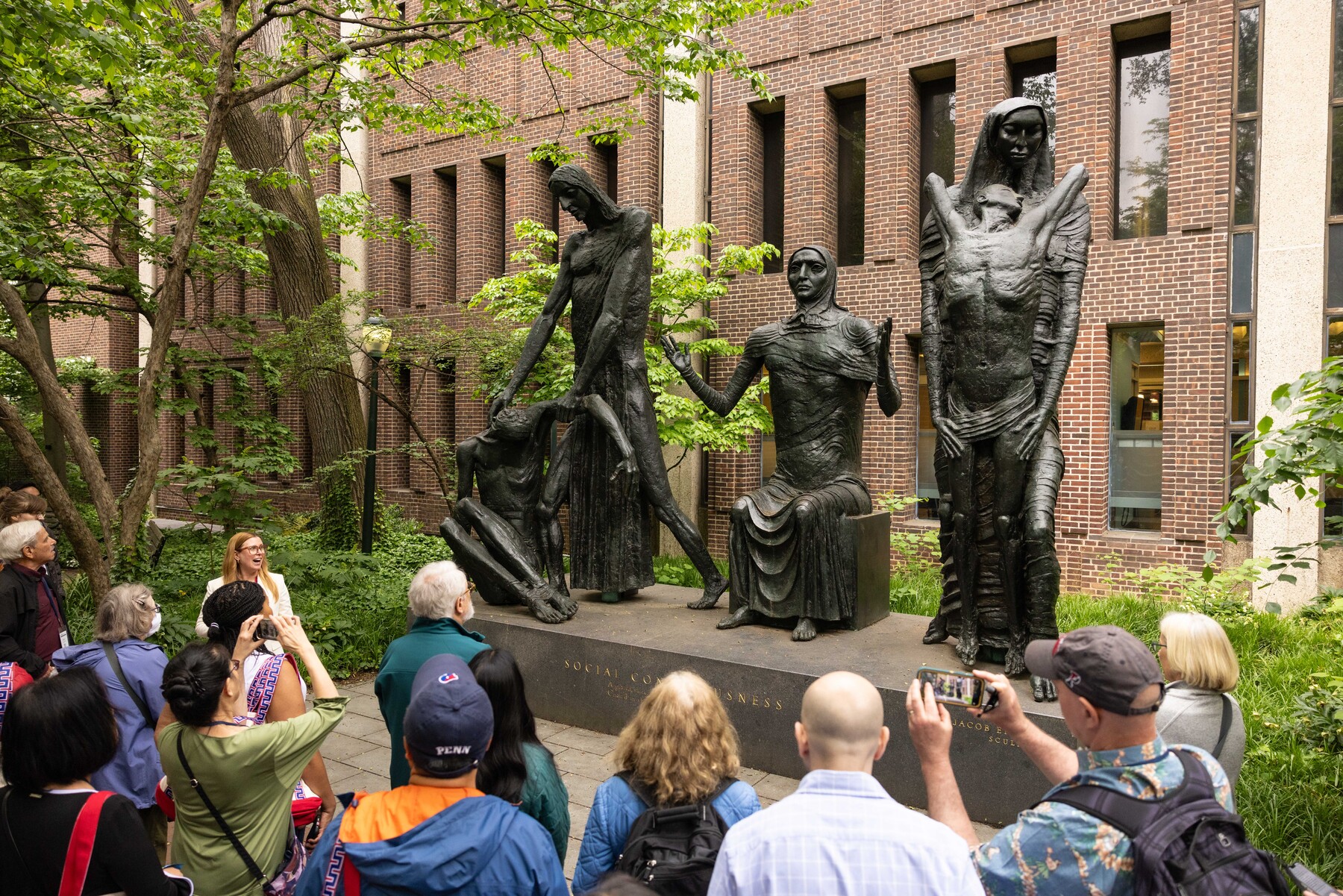 Director of the Penn Art Collection Lynn Smith Dolby explains a sculpture during a sculpture tour, participants snapping photos on their phone