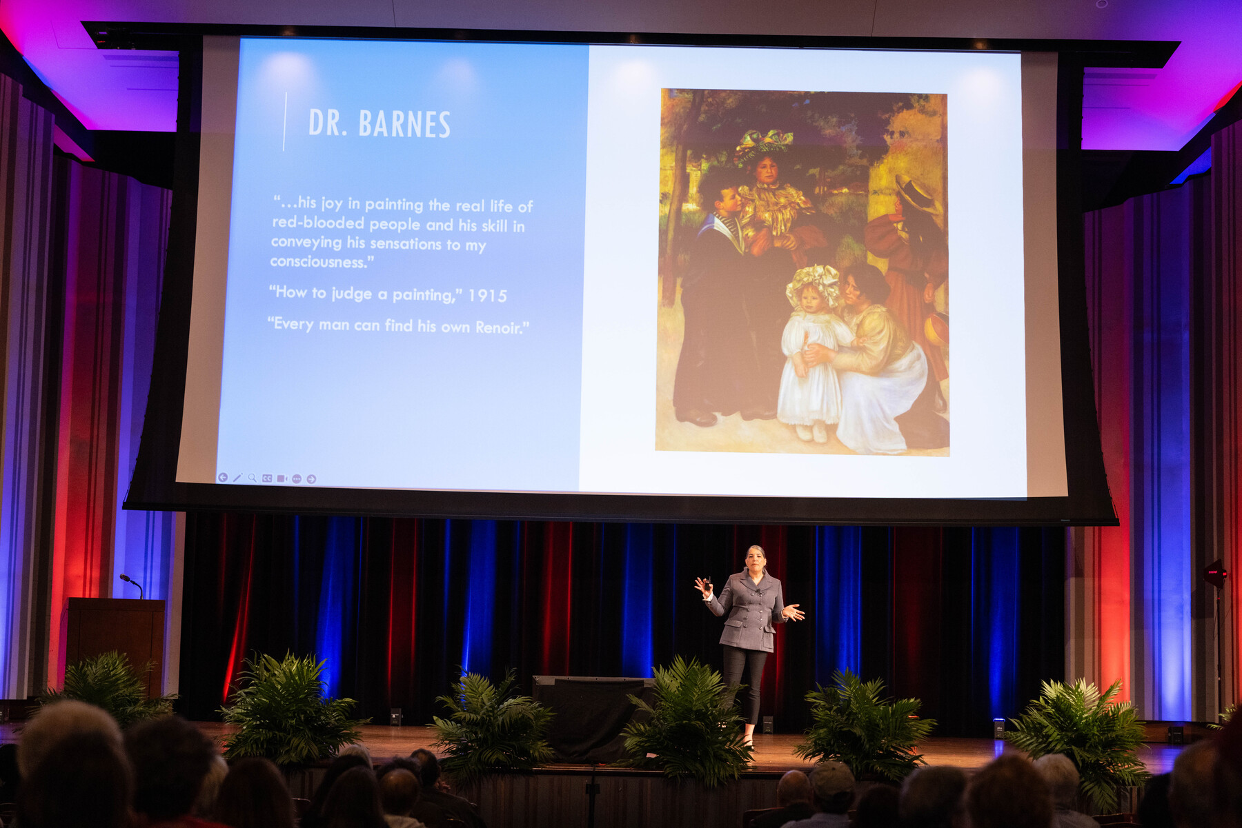 Shaw on stage with presentation in background describing Dr. Barnes
