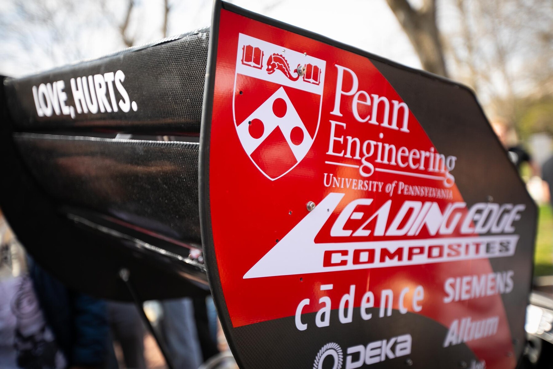 A side view of the REVX electric race car highlights the rear wing, cockpit, and team sponsor logos.