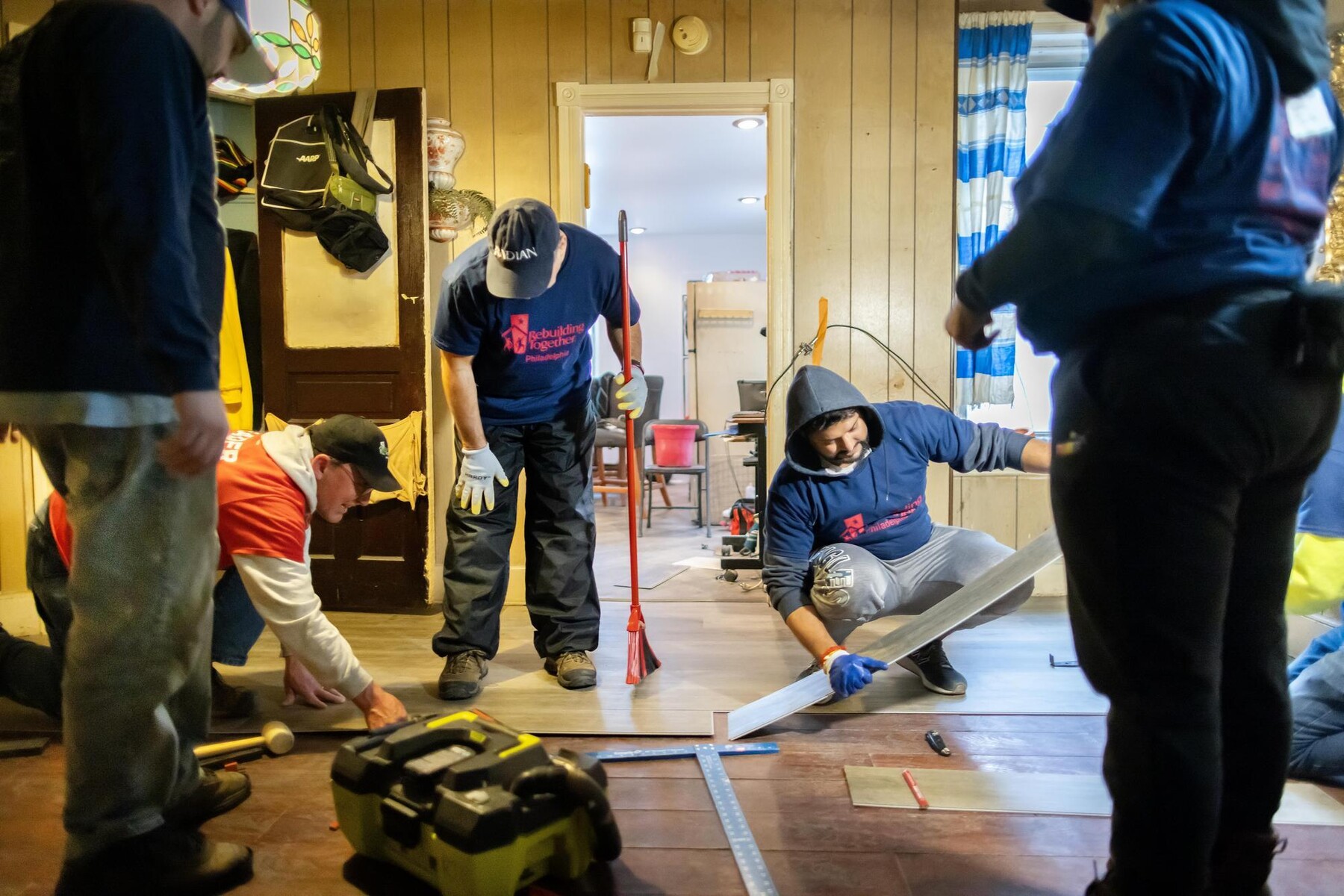 Volunteers installing floor tiles indoors during the block build.