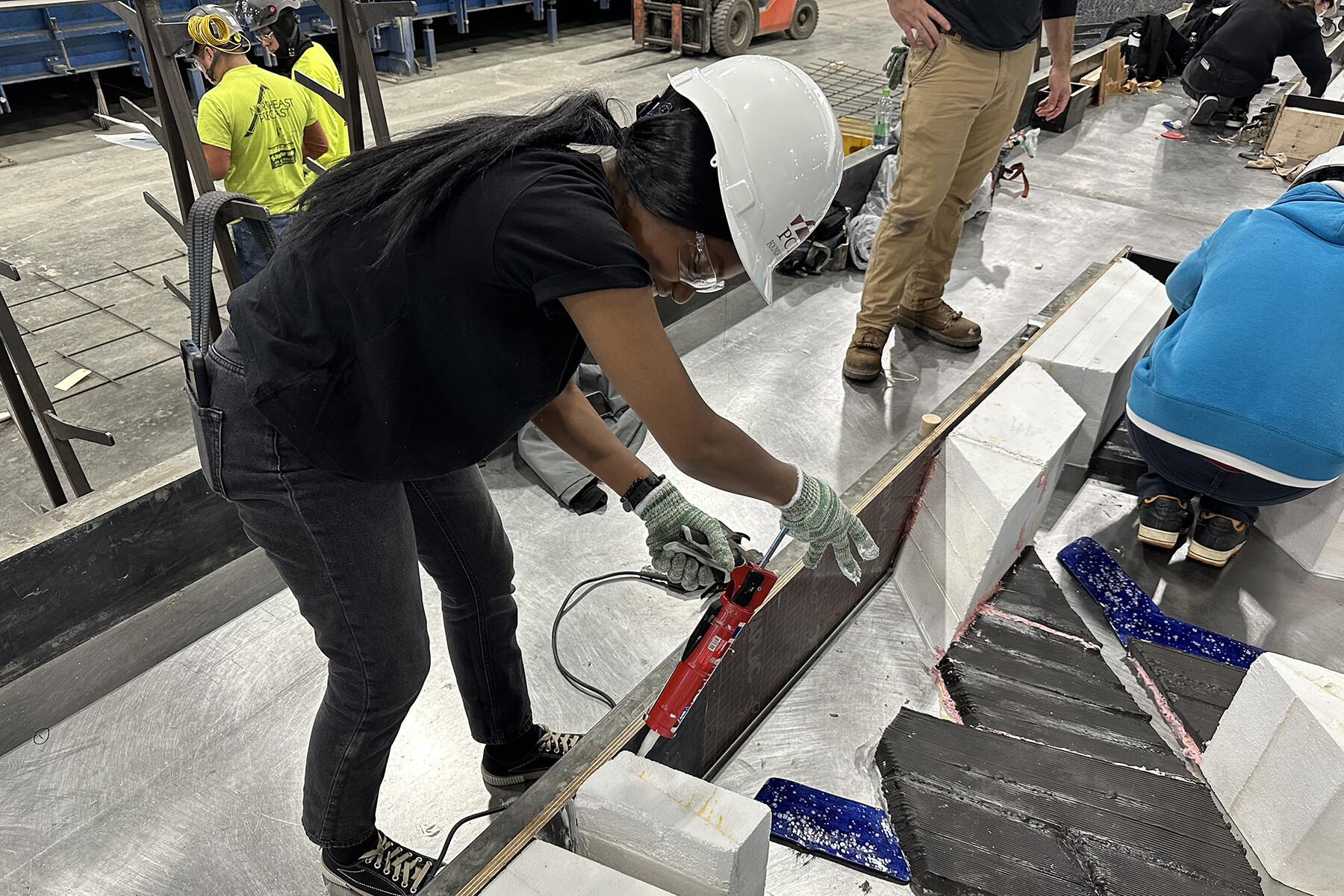 Students constructing the concrete panels in front of the Weitzman School in a large fabrication lab.