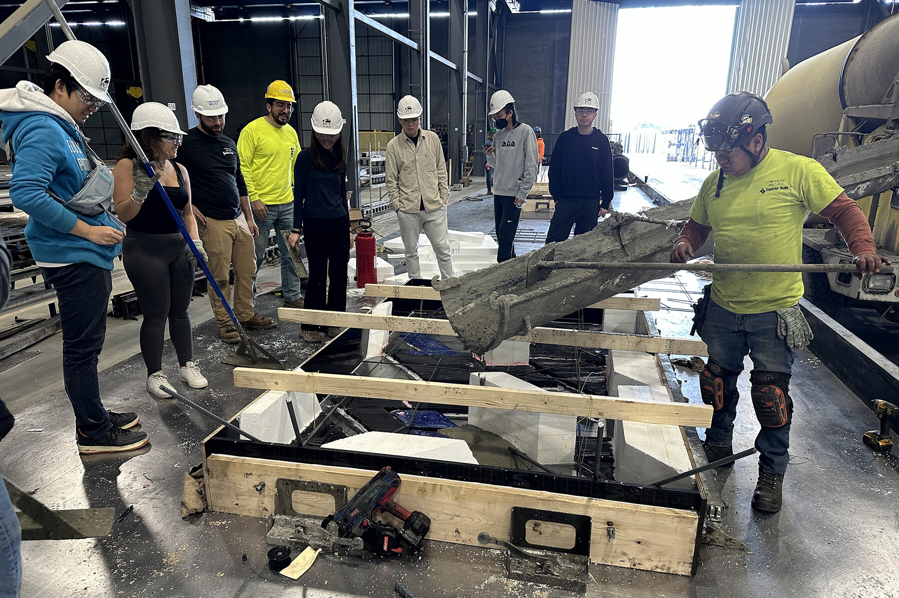 Students constructing the concrete panels in front of the Weitzman School in a large fabrication lab.