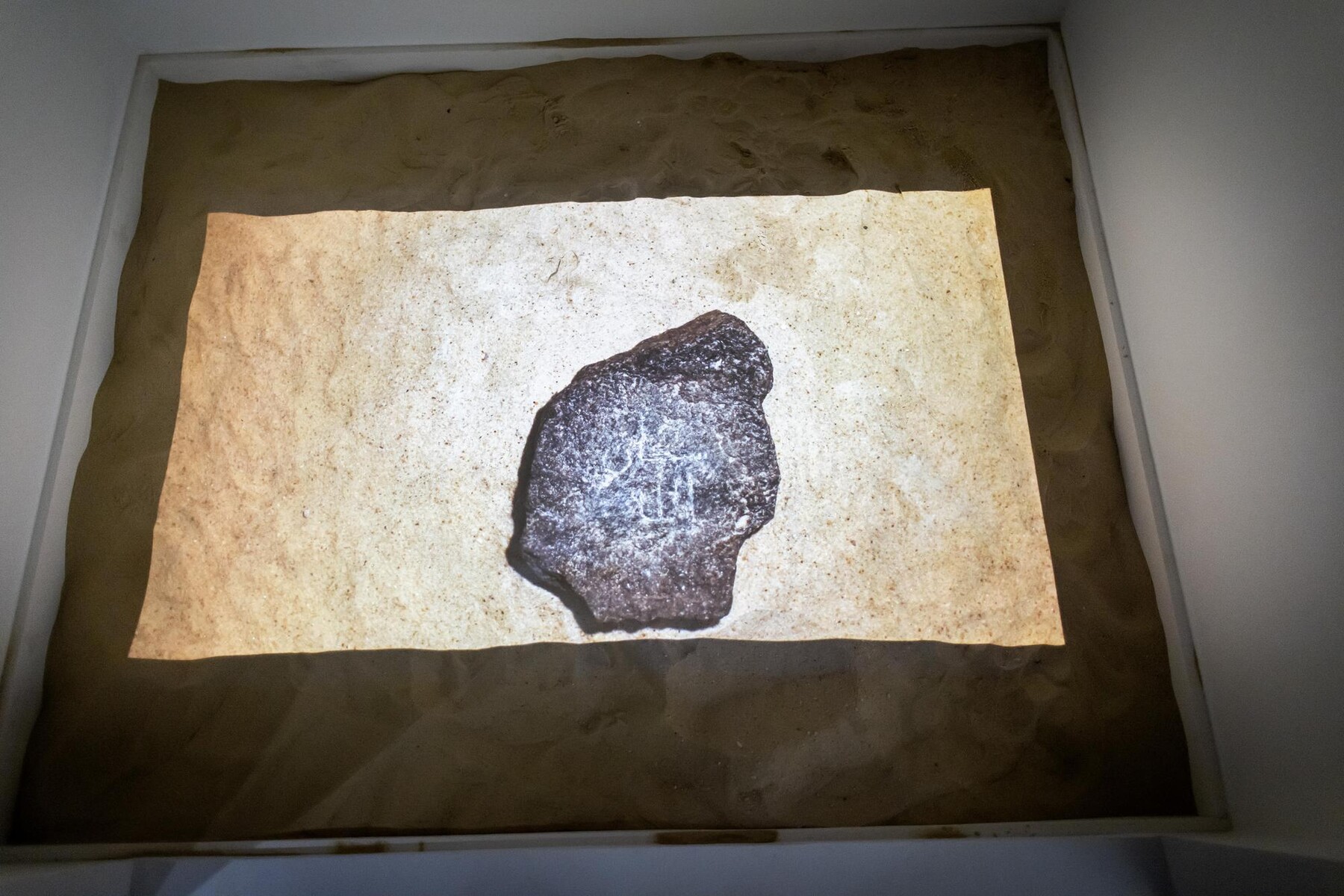 an illuminated rock on top of sand