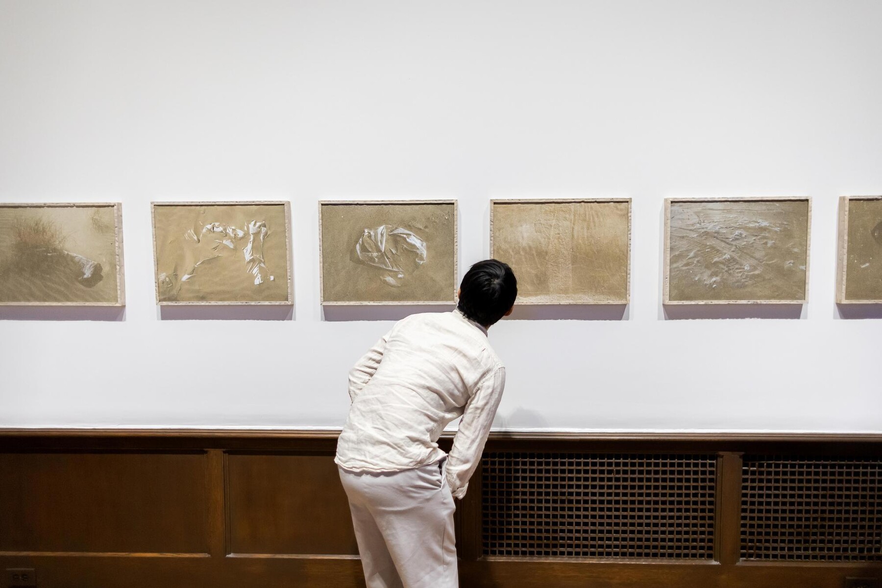 five artworks on the wall and one person looking at them
