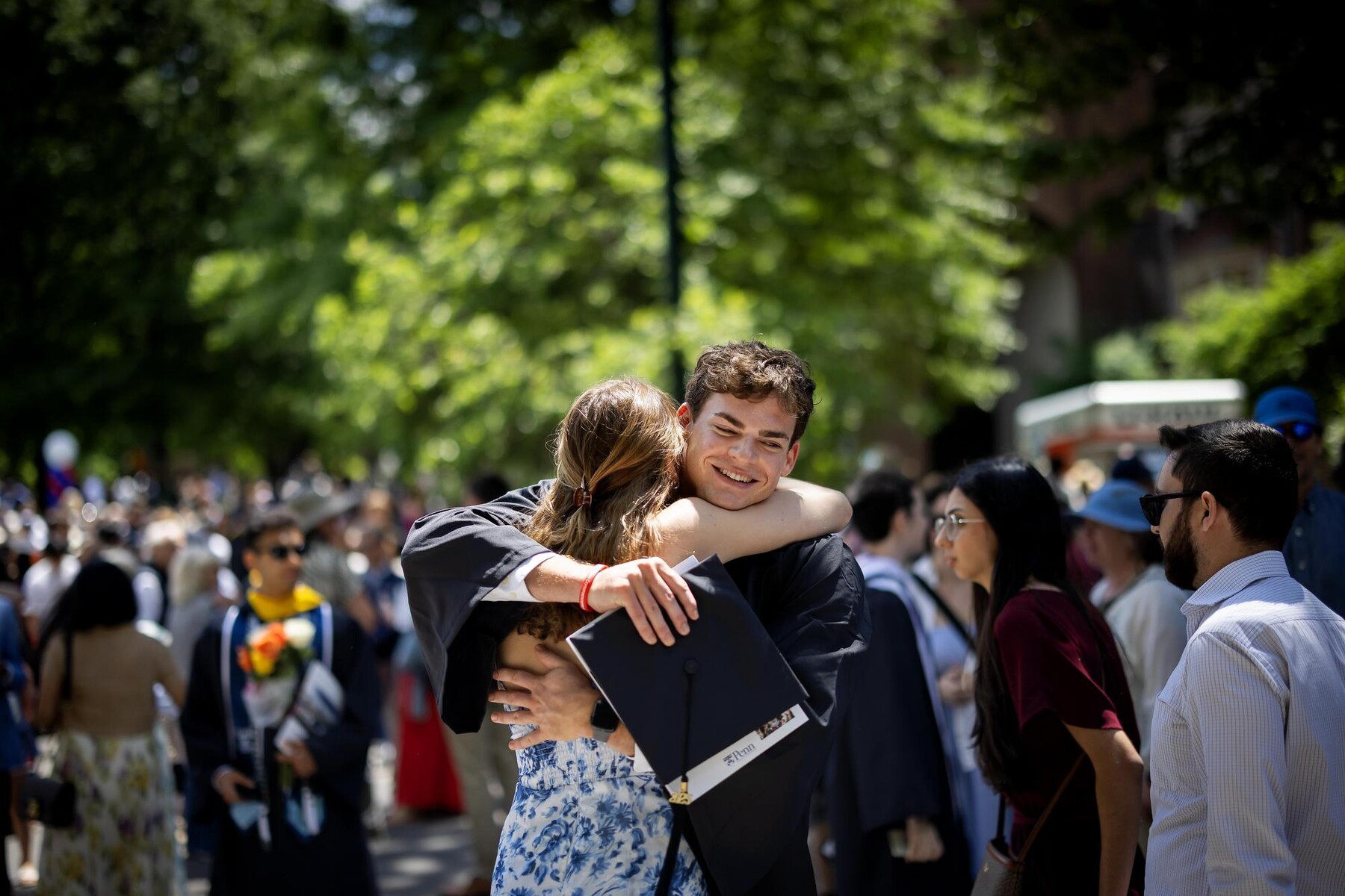 A graduate hugs someone after the Commencement ceremony.