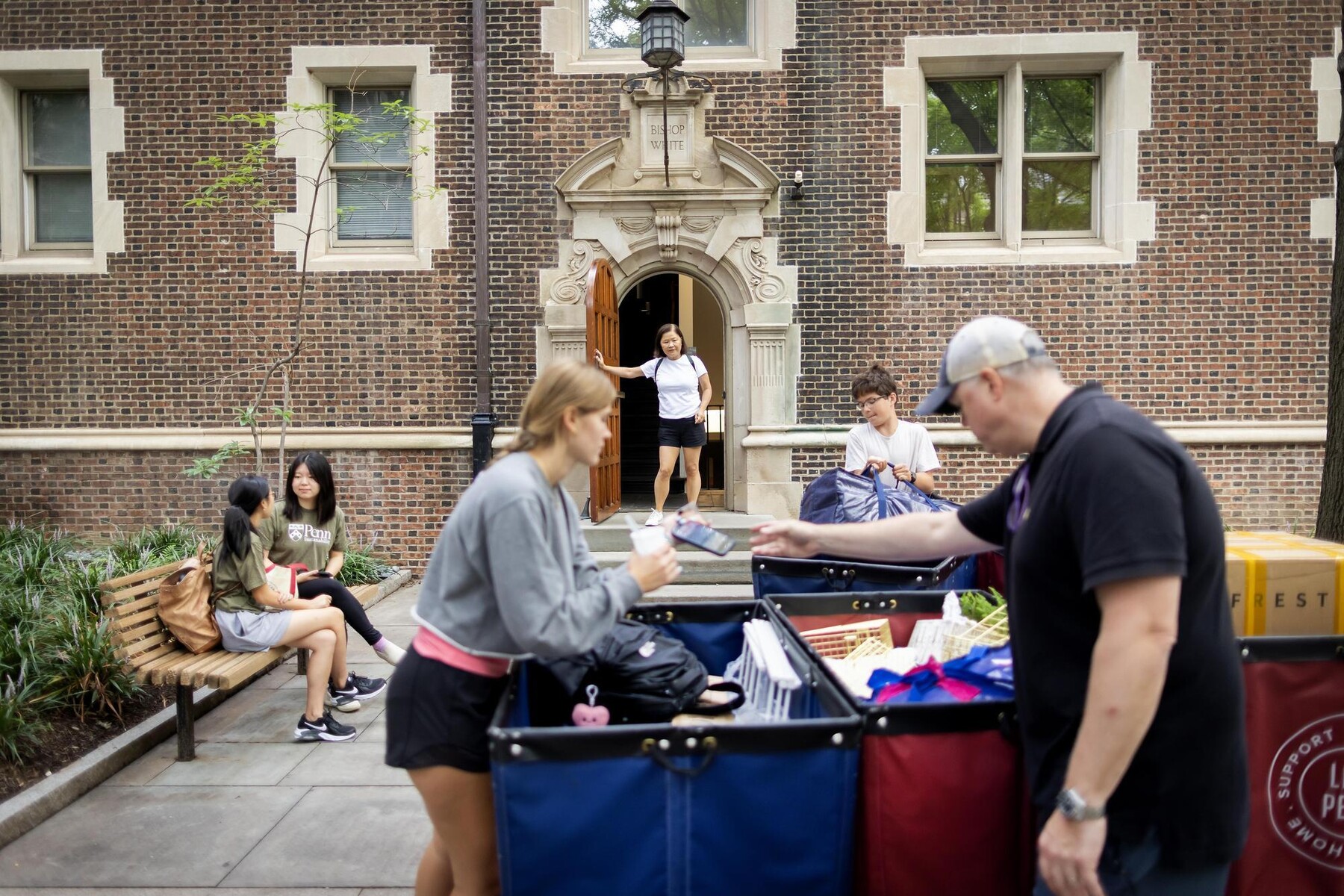 People unloading a Move-In cart in front of a College House on Penn’s campus.
