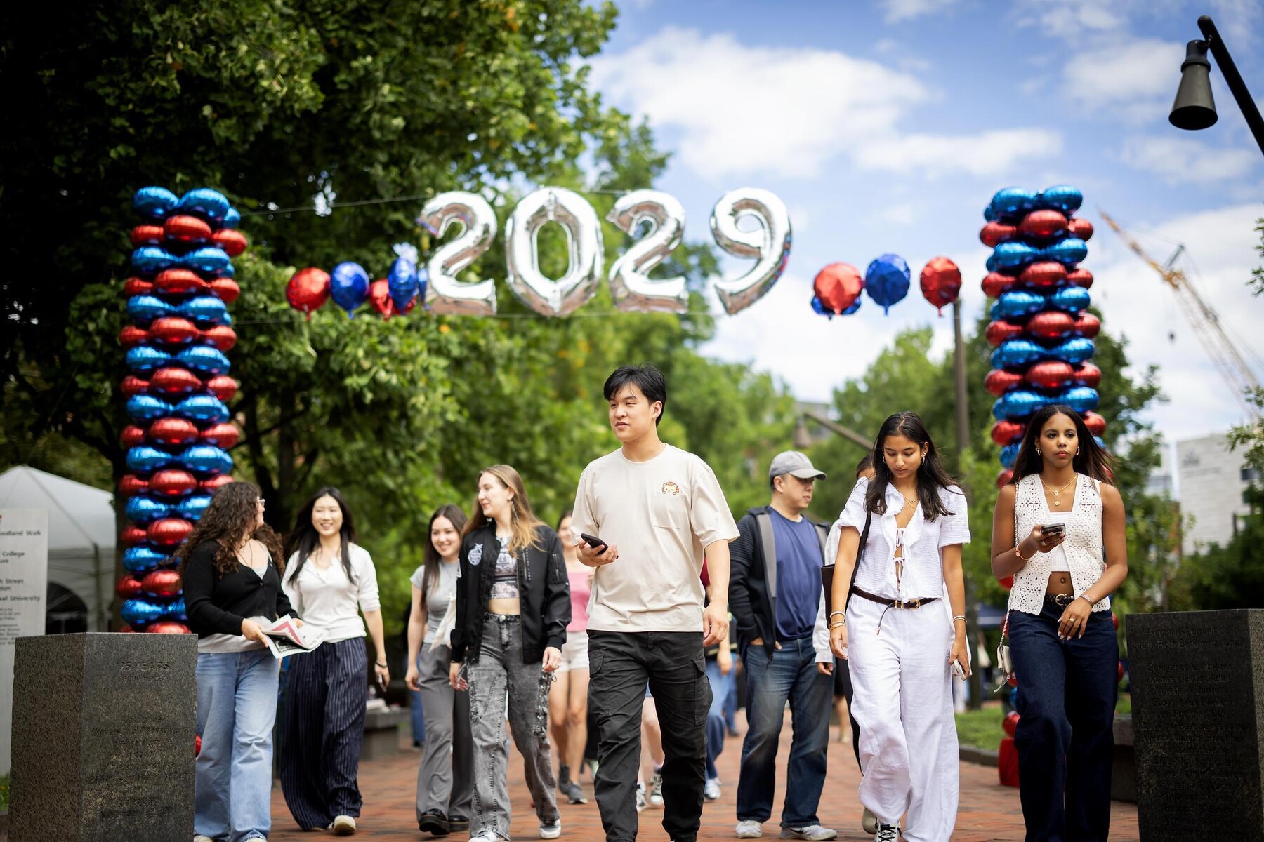 Students and families on Penn’s campus walking under a large 2029 balloon arch.