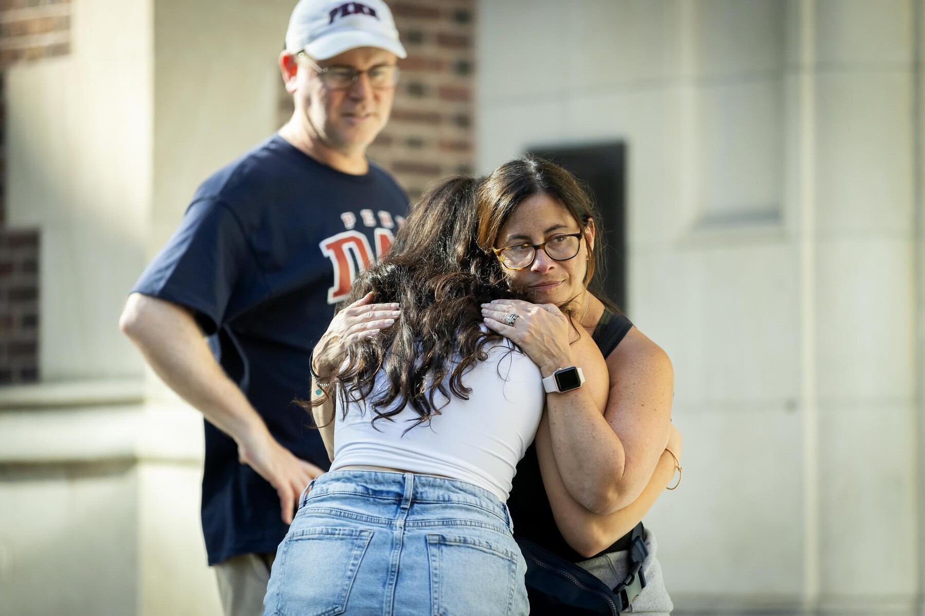 A family hugging outside of a College House on Move-In