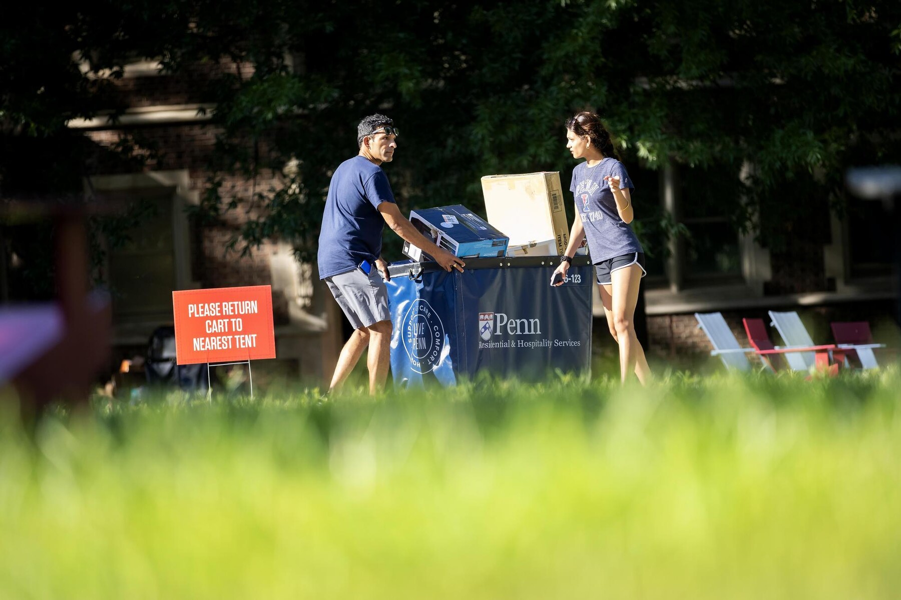 A parent helping their student push a Move-In cart.