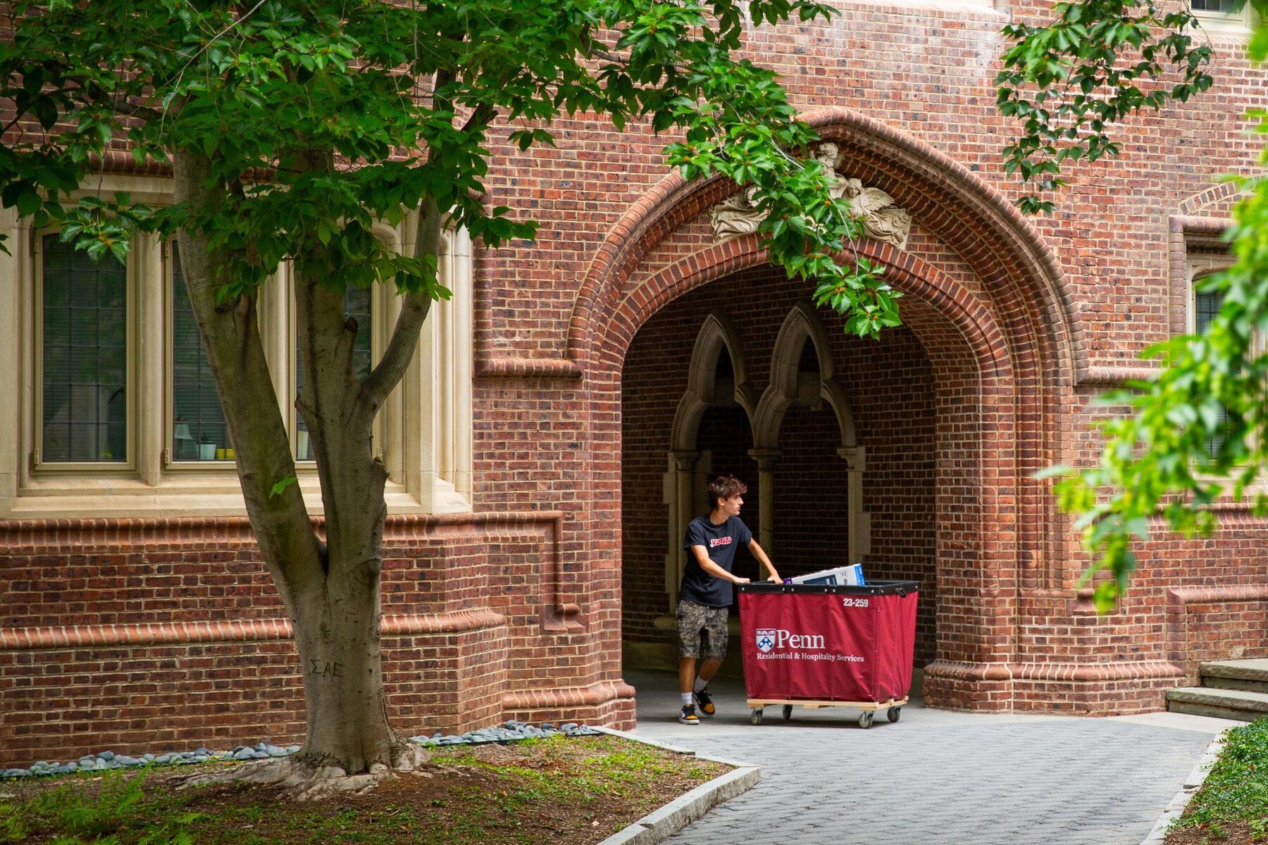 A student pushing a move-in cart outside a College House.