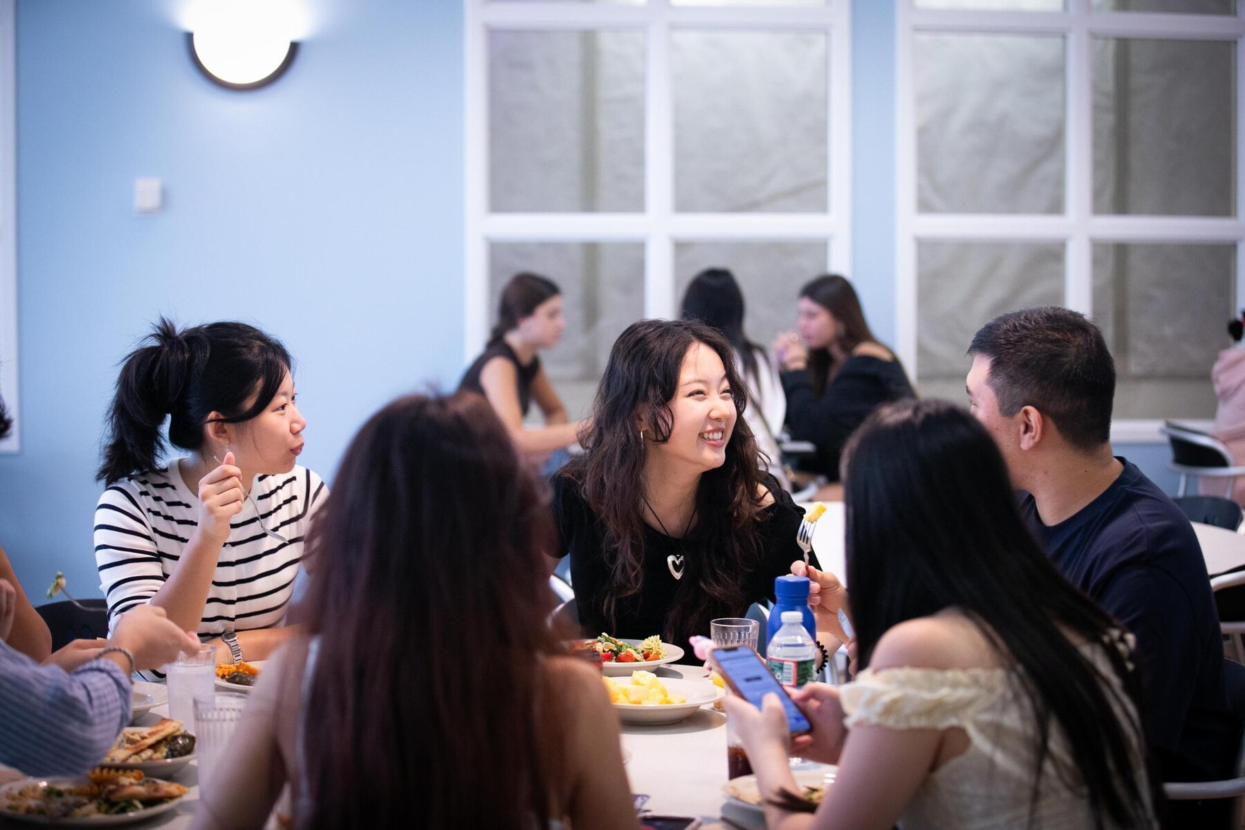 Five people talking and eating together at a table in Penn Dining during Move-In.