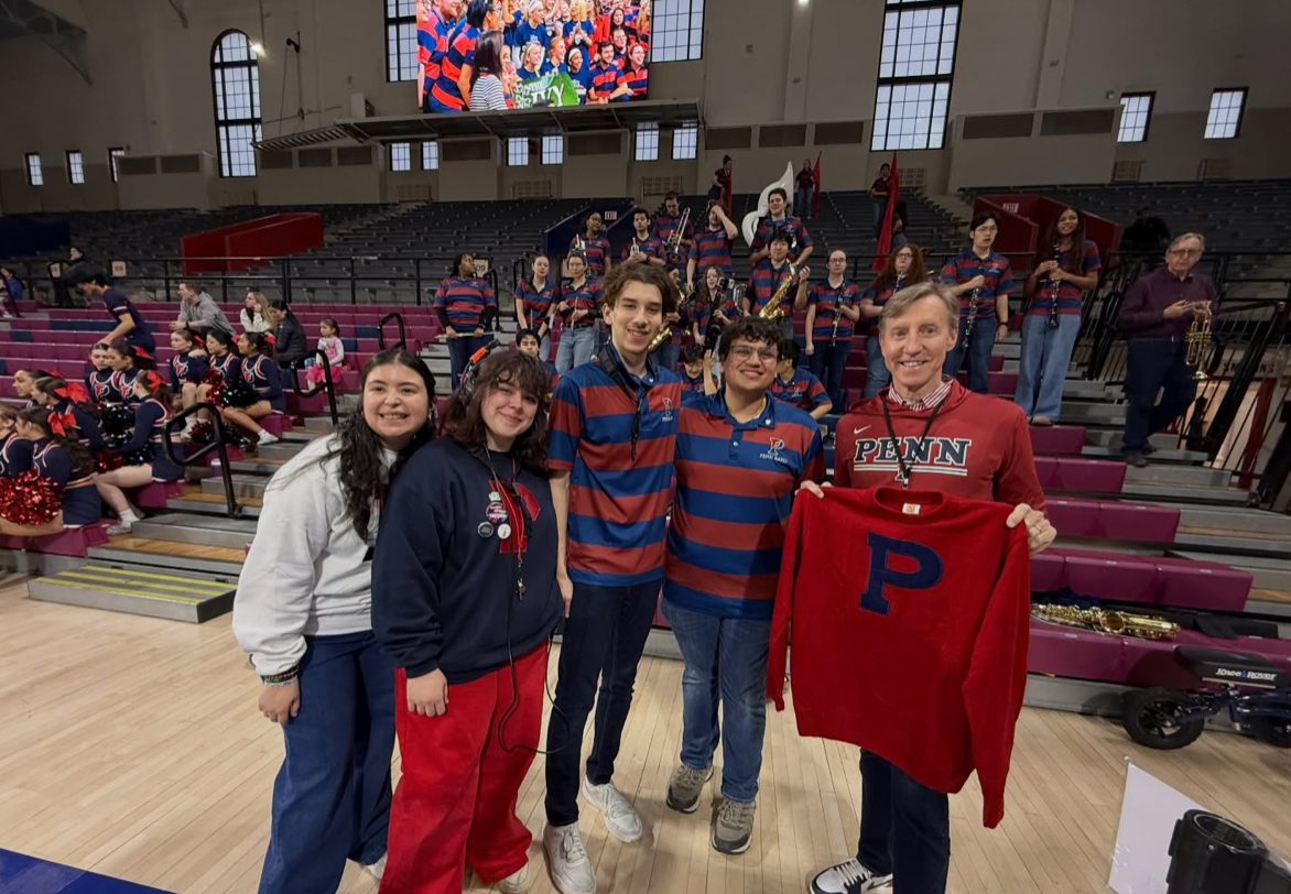 J. Larry Jameson holding a Penn sweatshirt on the court at the Palestra.