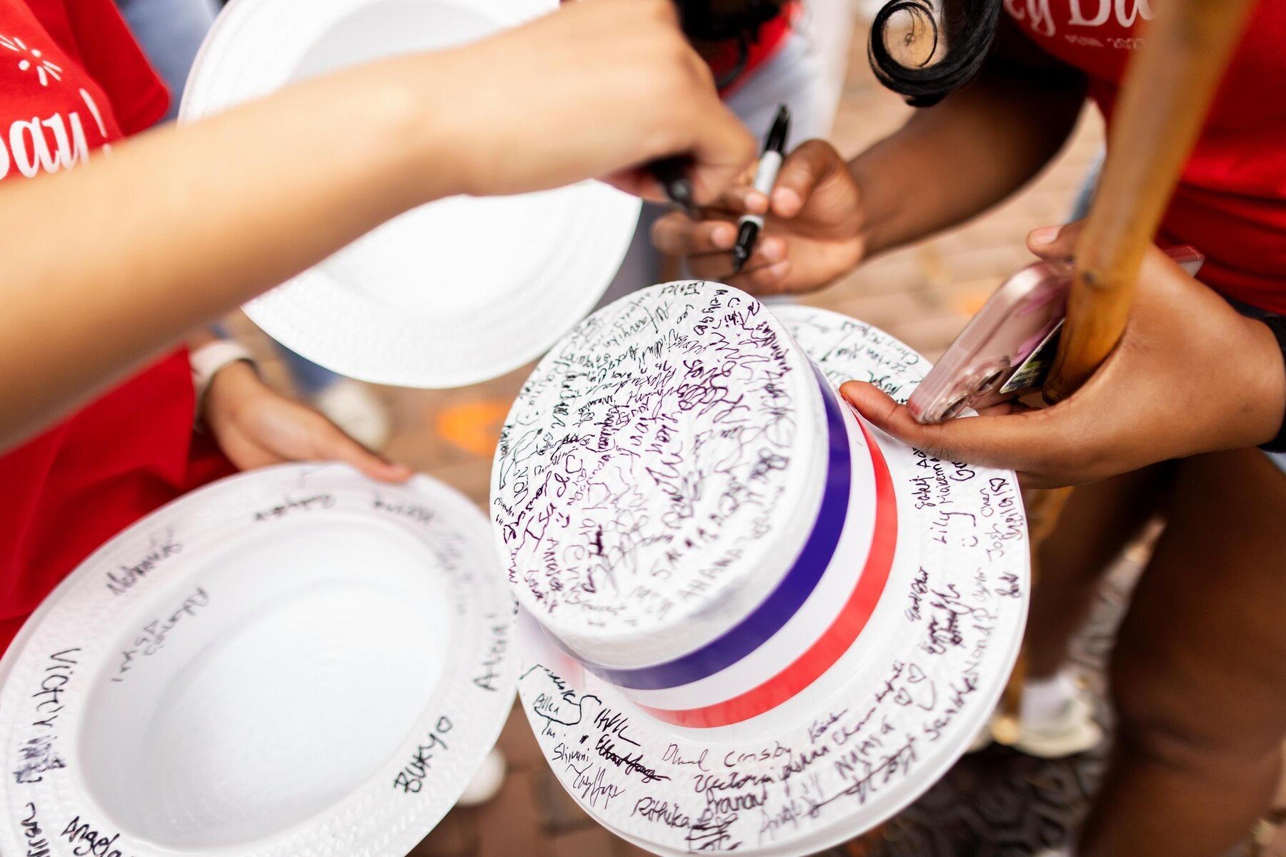 Students signing styrofoam hats with Sharpie’s during Hey Day.