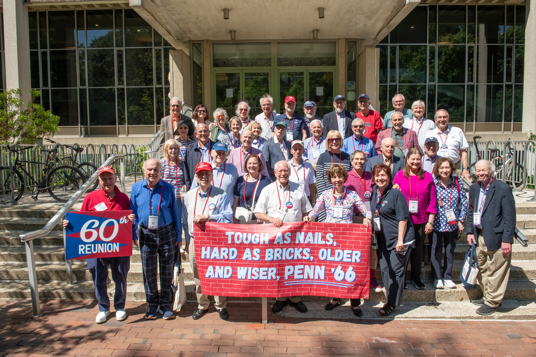 Penn alum on the steps of the library behind a banner celebrating their 60th reunion.