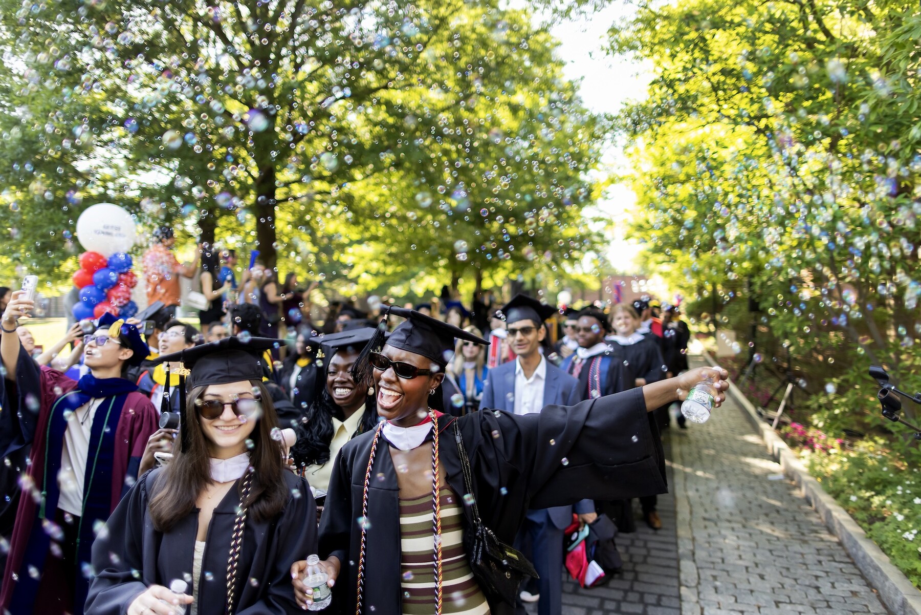 students walking down locust walk in regalia towards commencement.
