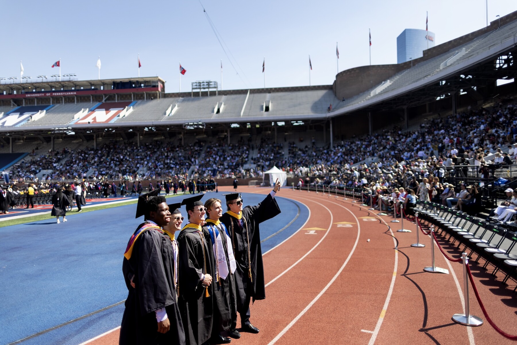 Students standing on Franklin Field waving to the crowd at commencement.