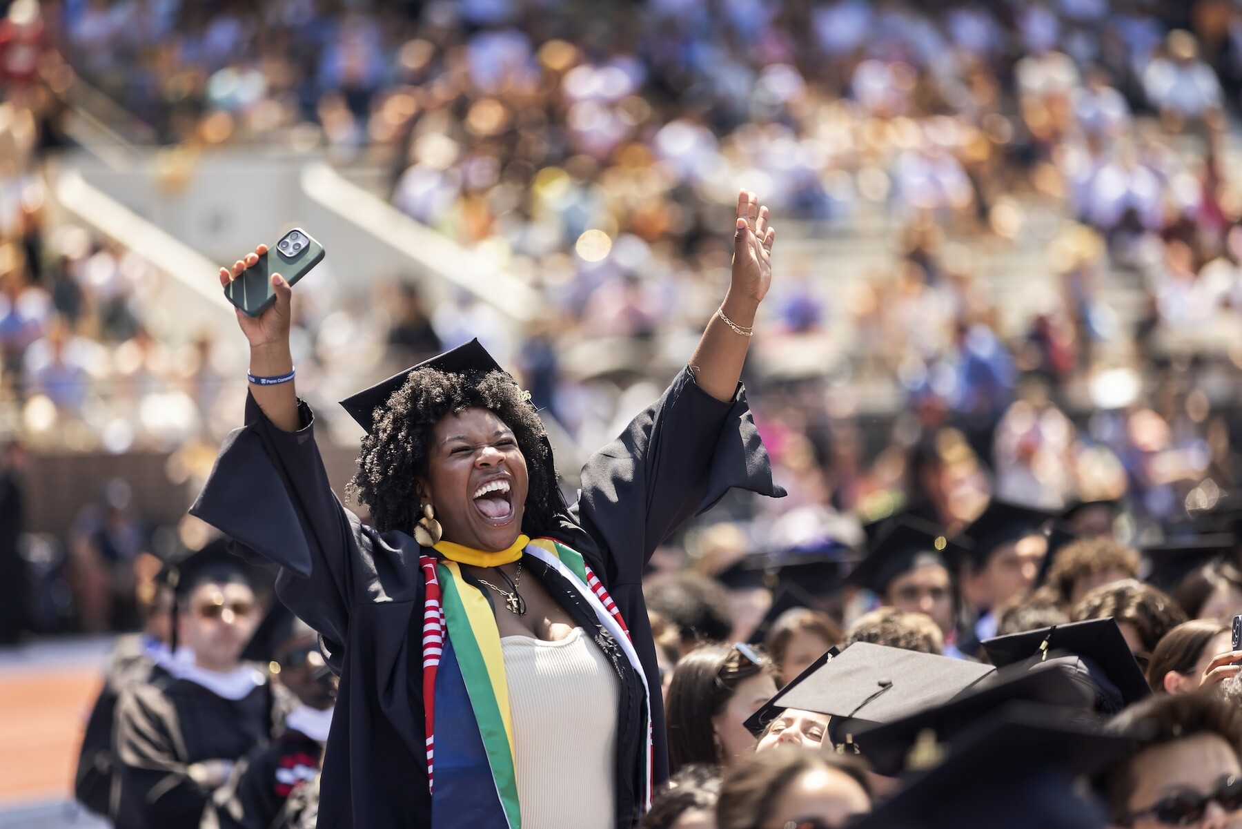 A graduate waving their arms in celebration on Franklin Field during commencement