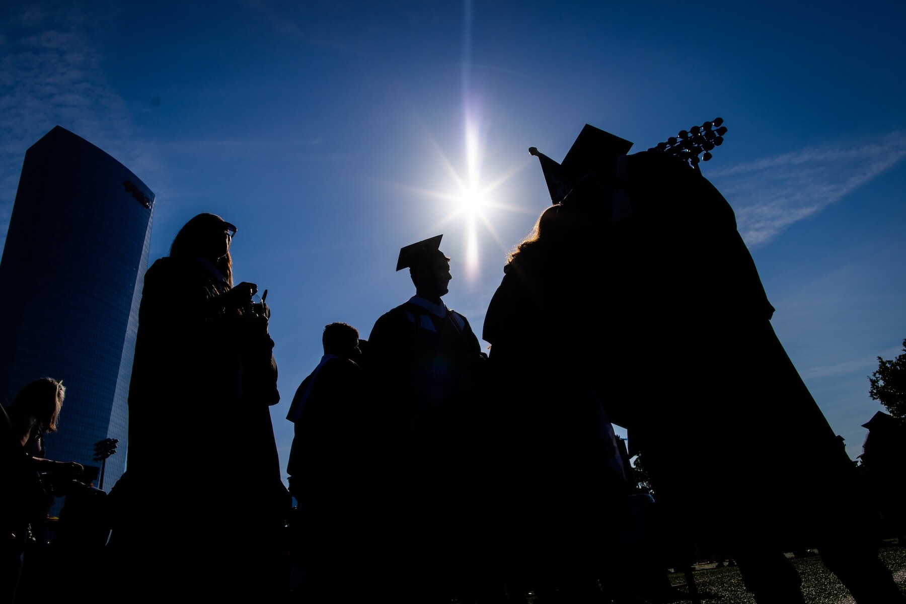 Graduates in silhoutte walking towards commencement