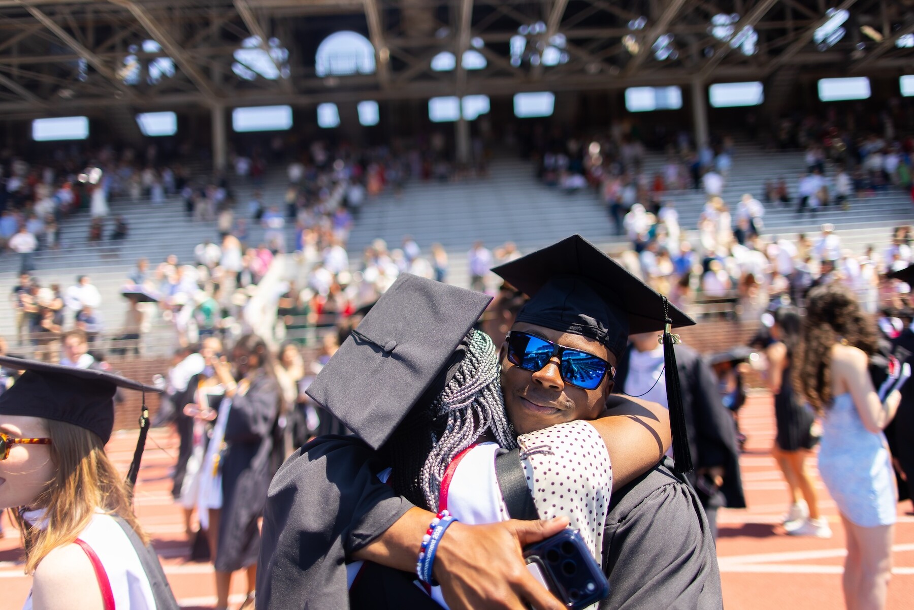 Two graduates hugging on franklin field after commencement.