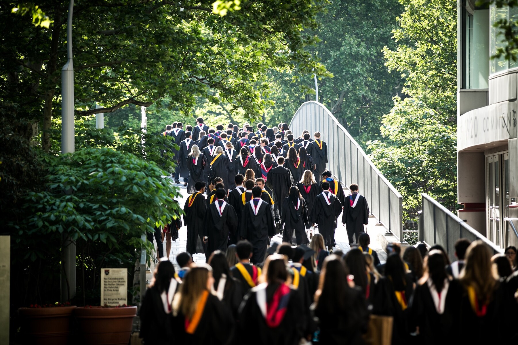 Graduates in regalia walking up Locust Bridge towards commencement.